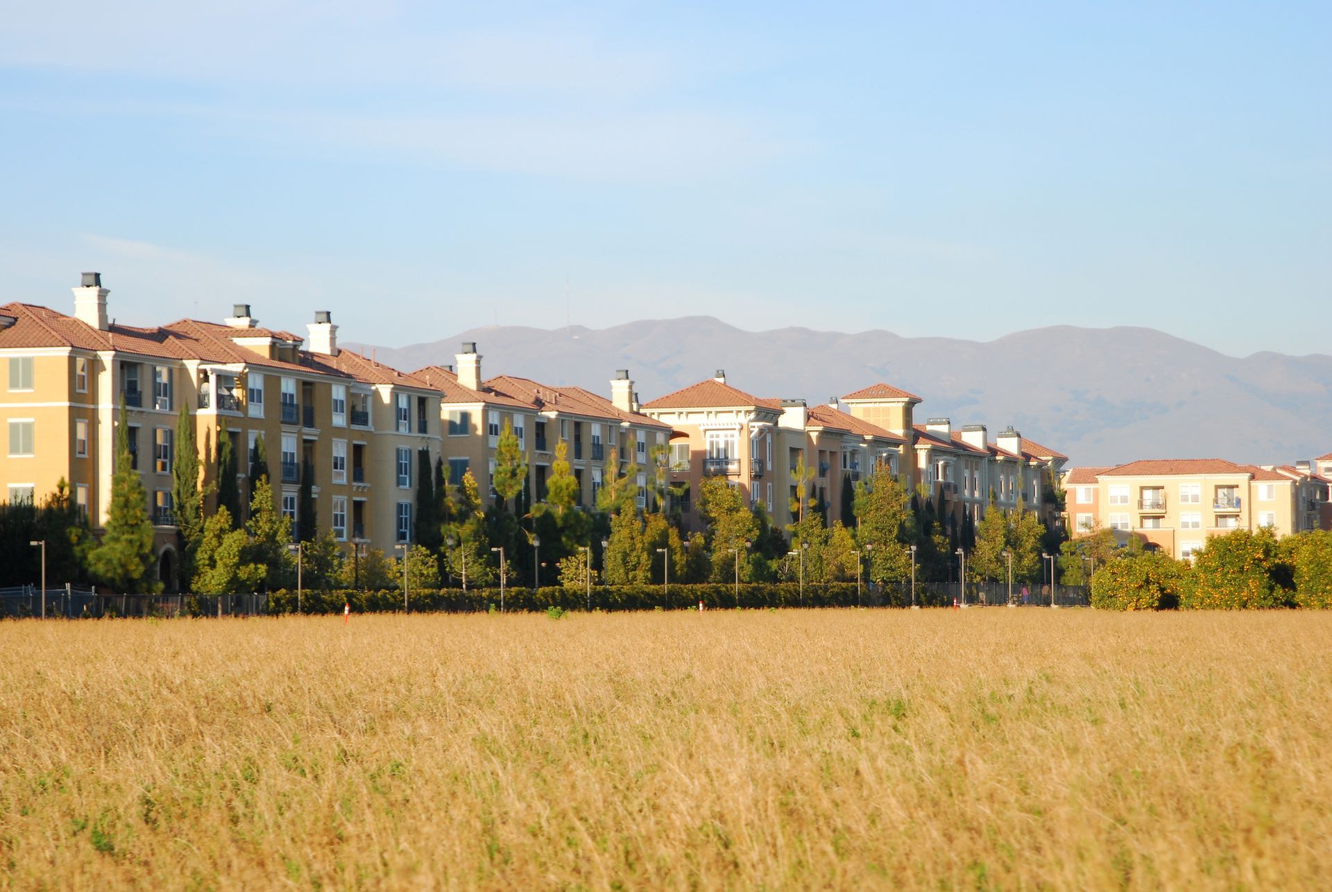 White stucco storefronts with stone columns under a clear blue sky.