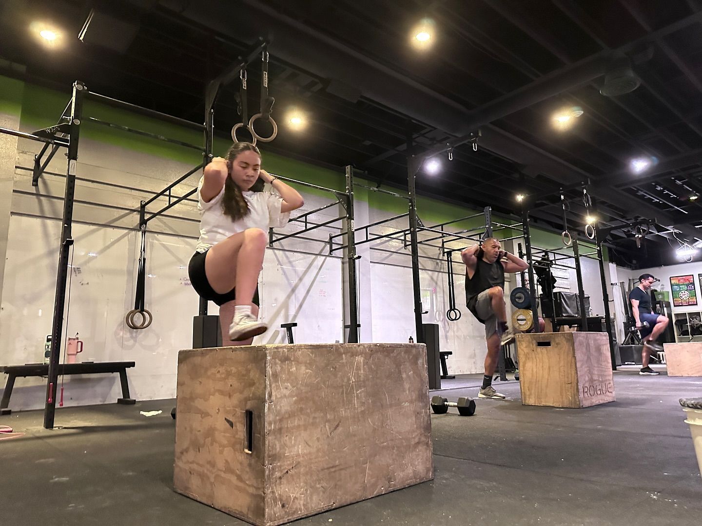 A woman is doing sit ups on a box in a gym.