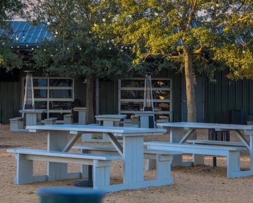 A row of picnic tables and benches in front of a building