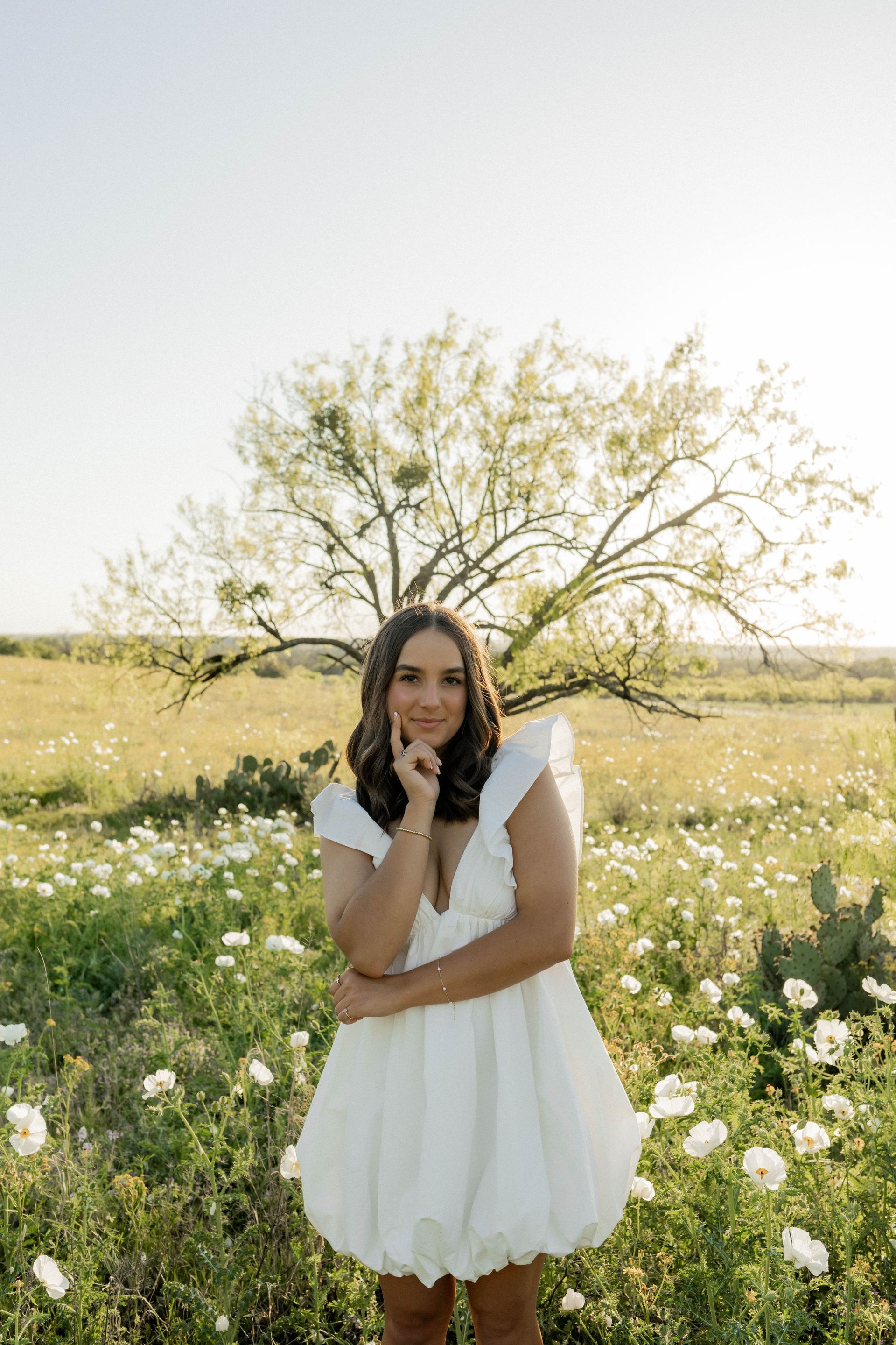 A woman in a white dress is standing in a field of flowers.