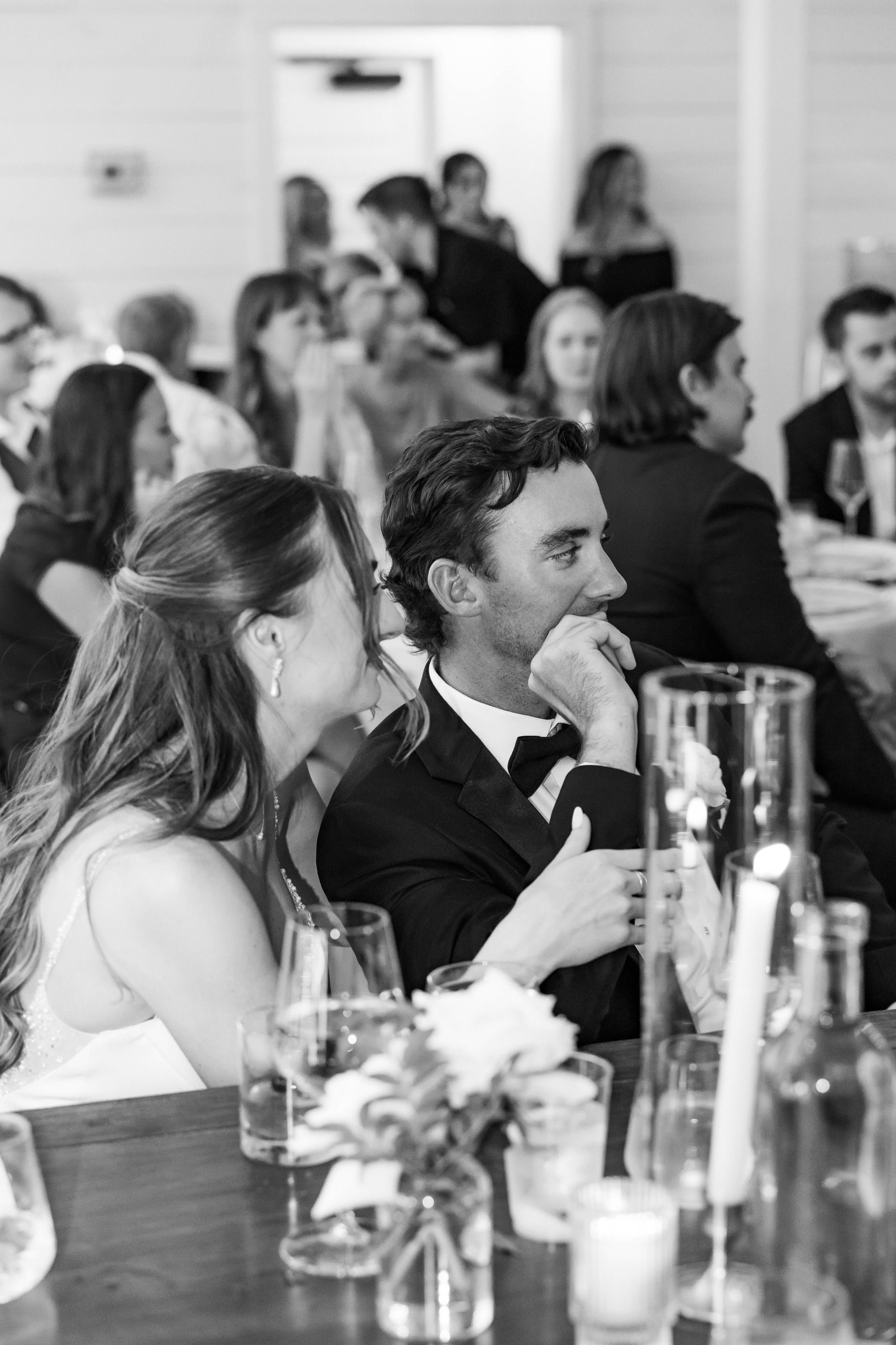 A bride and groom are sitting at a table at a wedding reception.