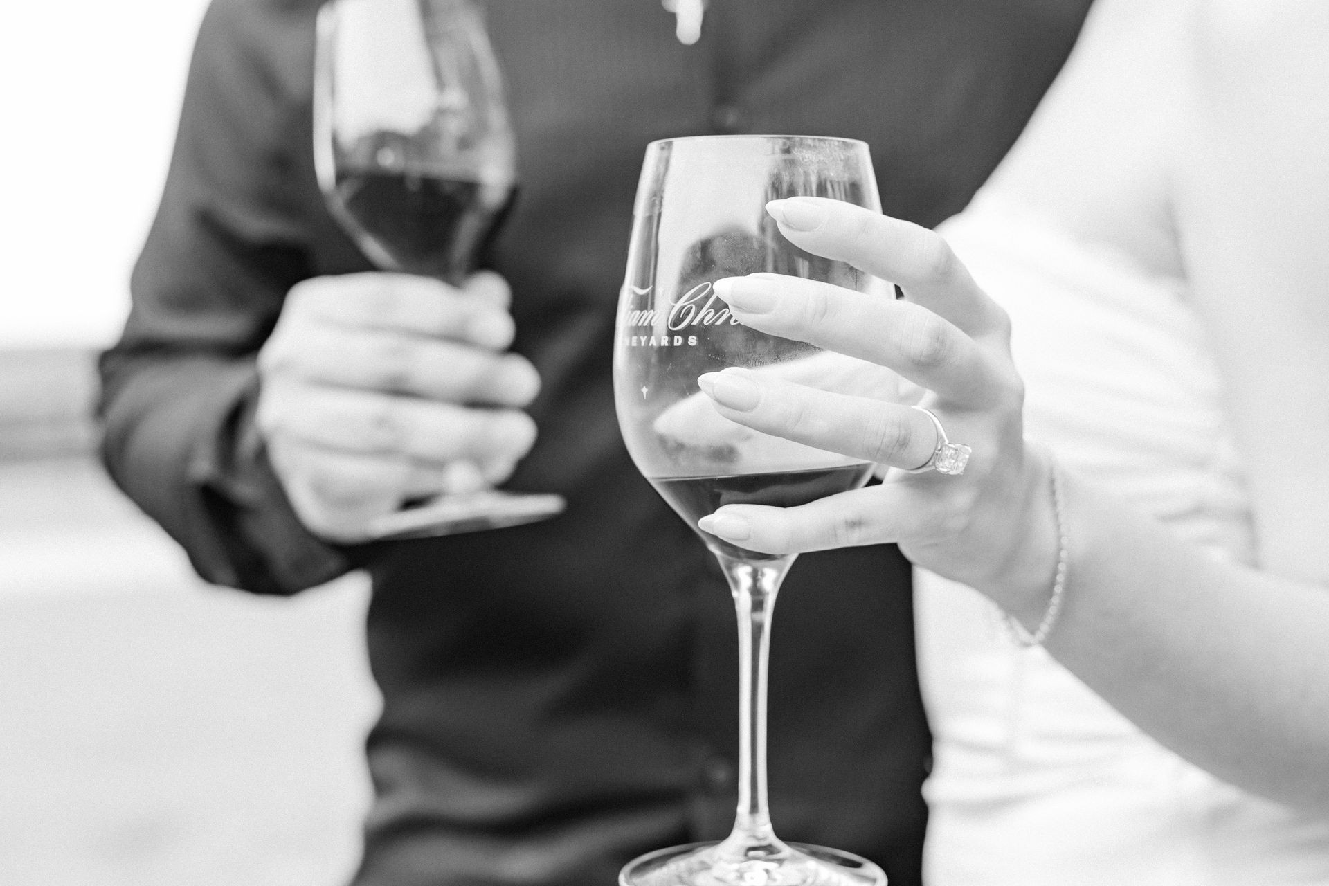 A black and white photo of a bride and groom toasting with wine glasses.