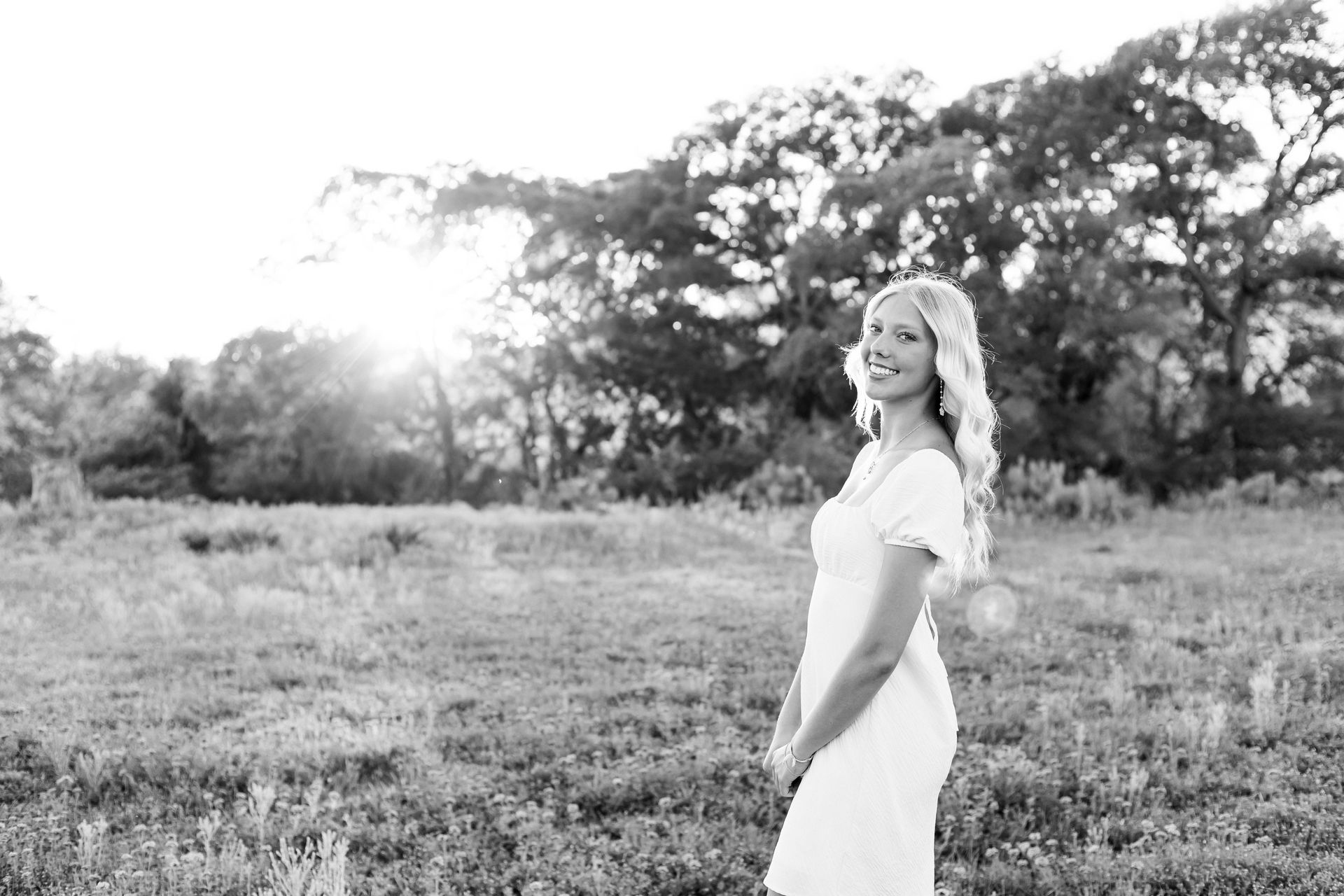 A woman in a white dress is standing in a field.