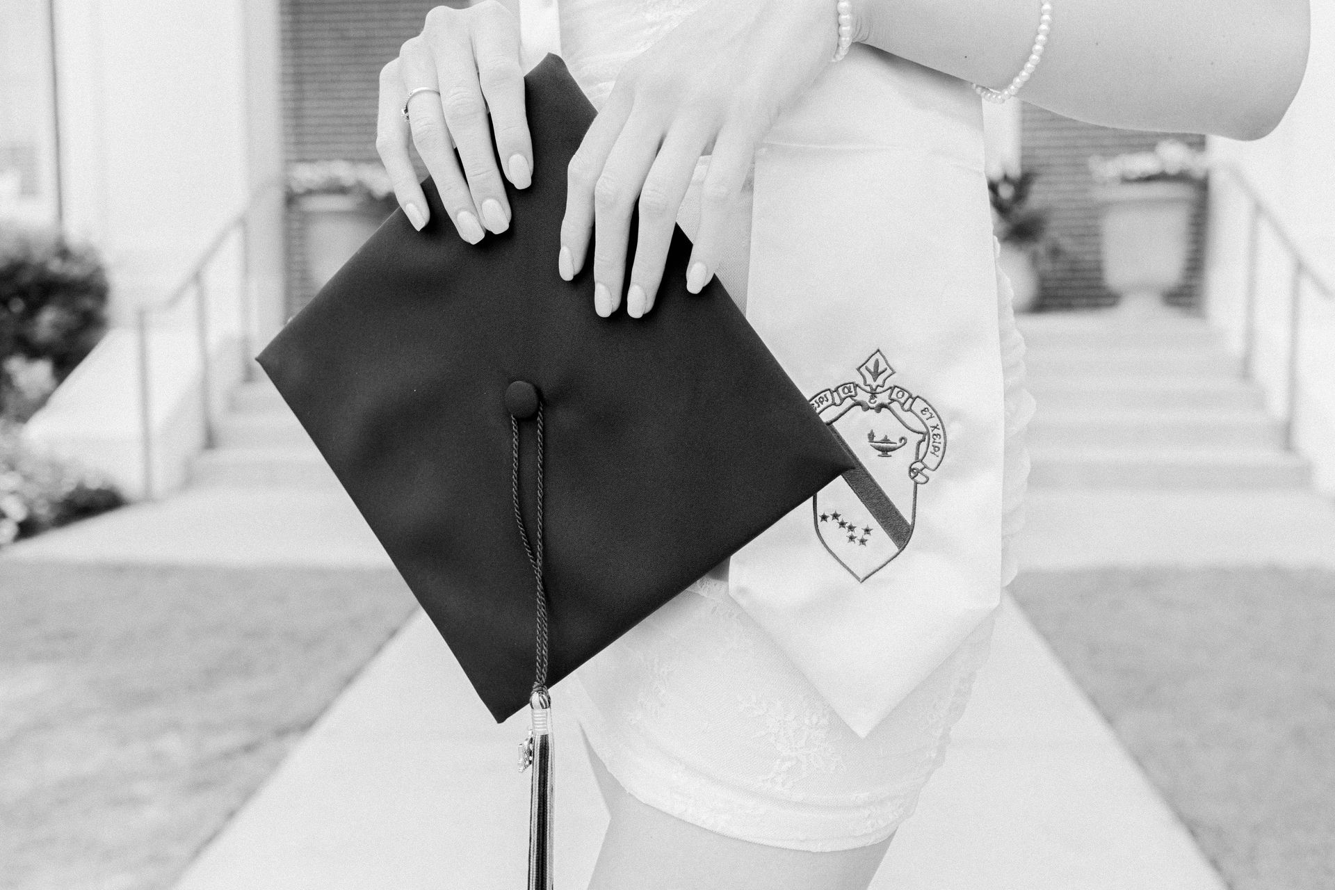 A black and white photo of a woman holding a graduation cap.
