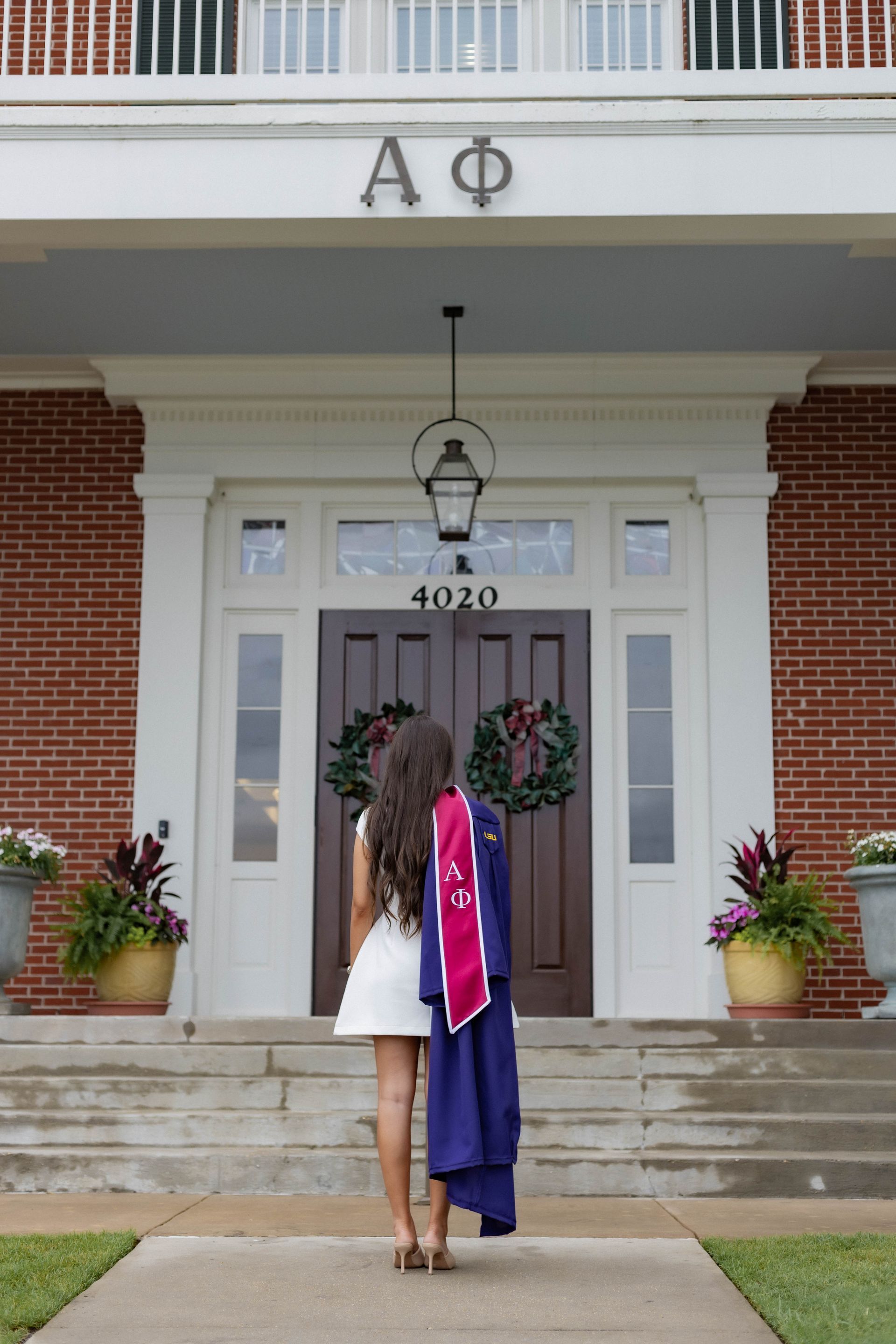 A woman in a cap and gown is standing in front of a building with the letter a on it