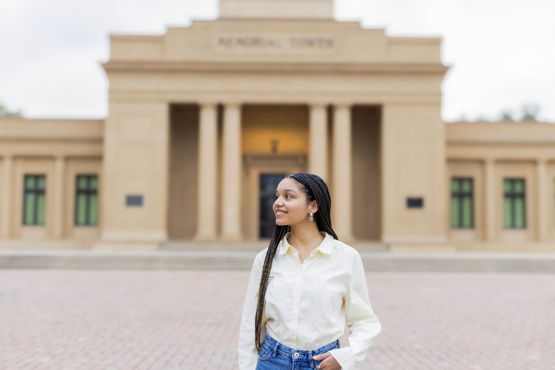 A woman is standing in front of a large building.