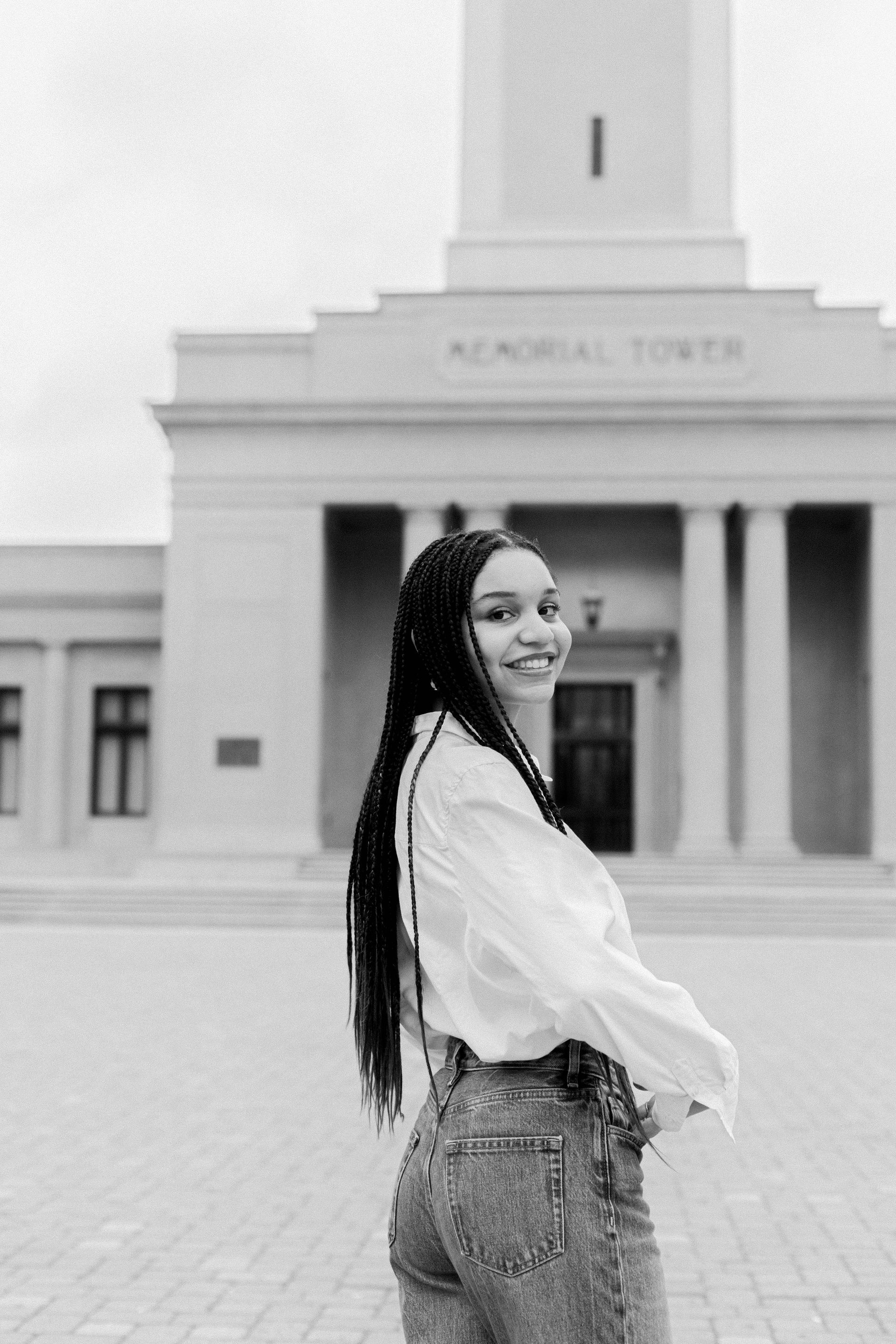 A black and white photo of a woman standing in front of a building.
