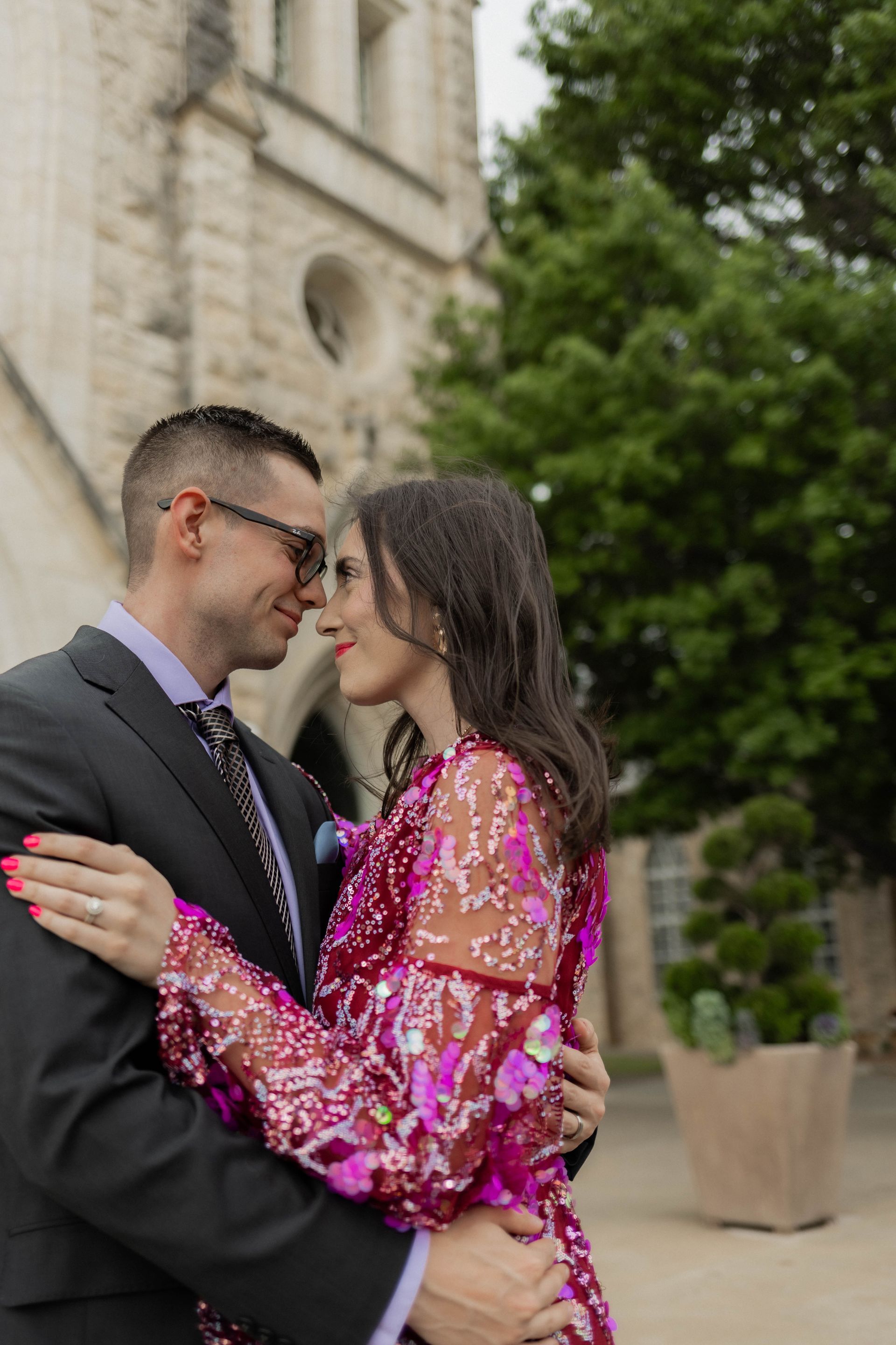 A man in a suit and tie is hugging a woman in a pink dress.