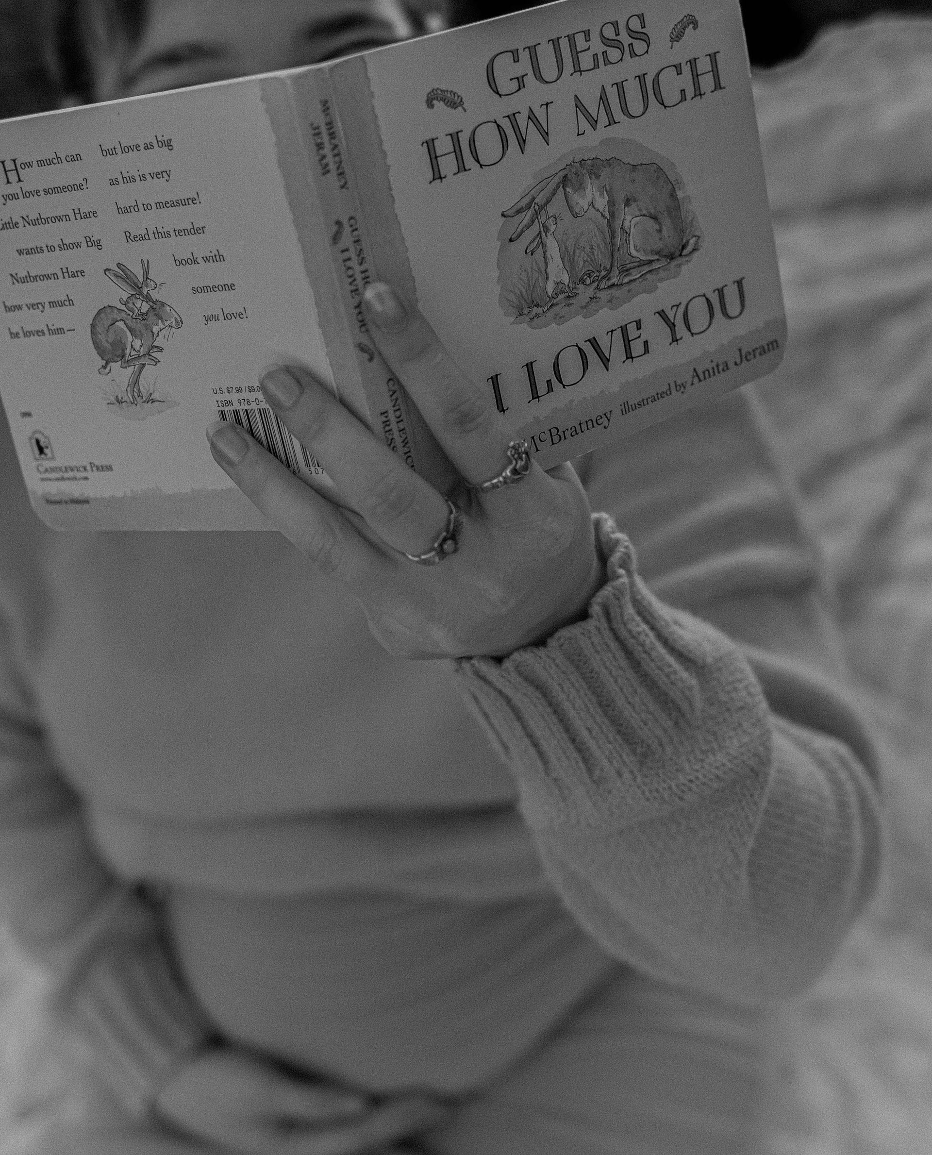 A woman is reading a book titled guess how much i love you