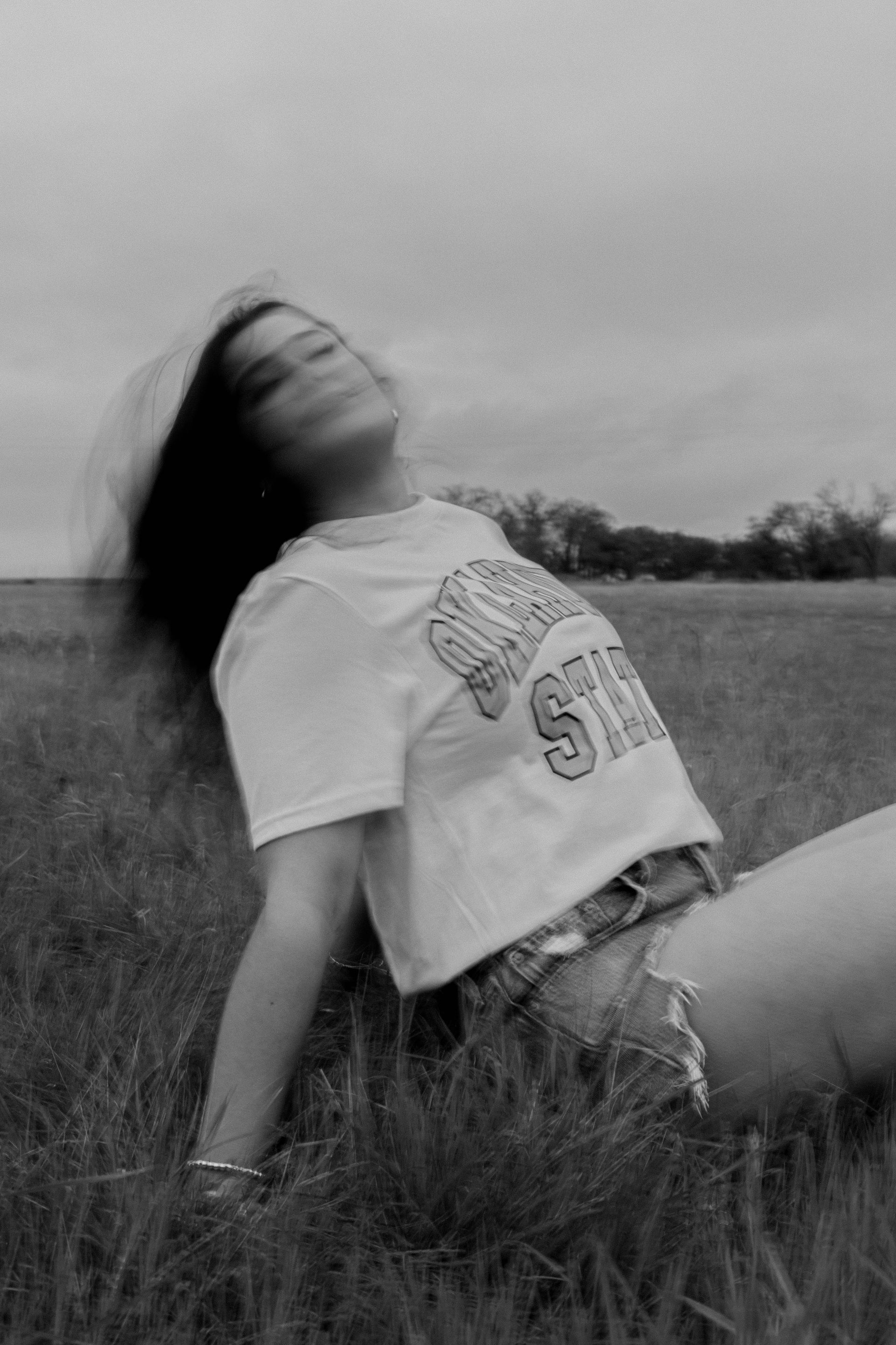 A black and white photo of a woman laying in the grass.