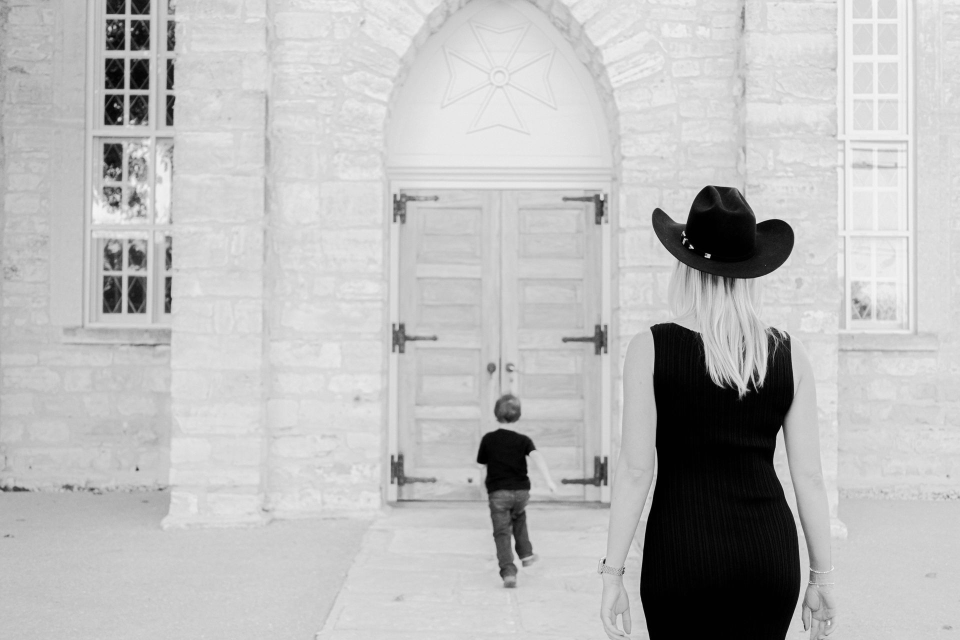A woman and a child are walking in front of a building.