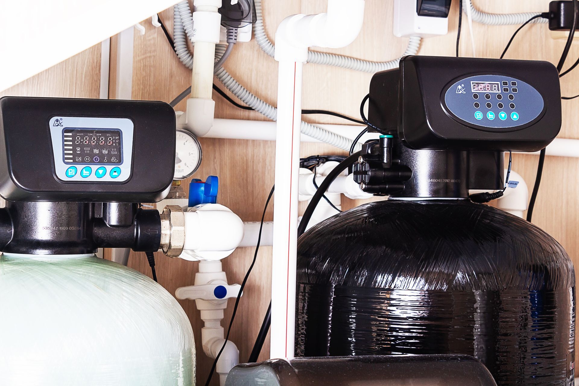 Water filtration tanks with digital control valves and connected plumbing system.
