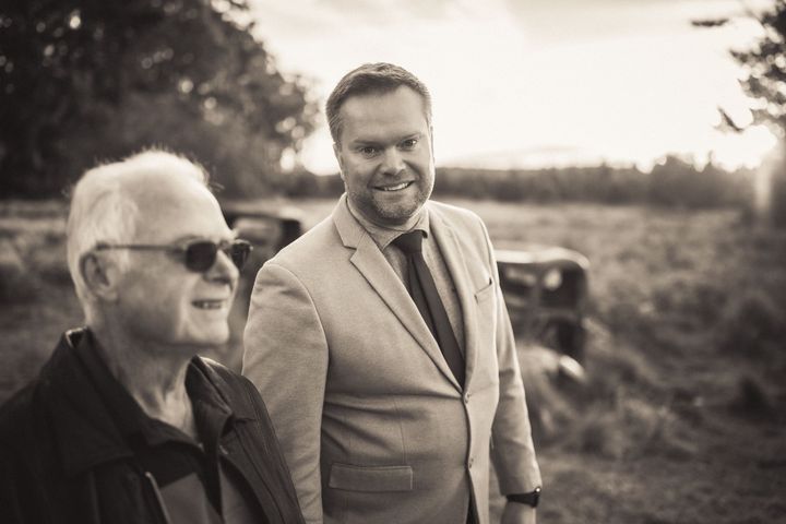 Two men in suits and ties are standing next to each other in a field.