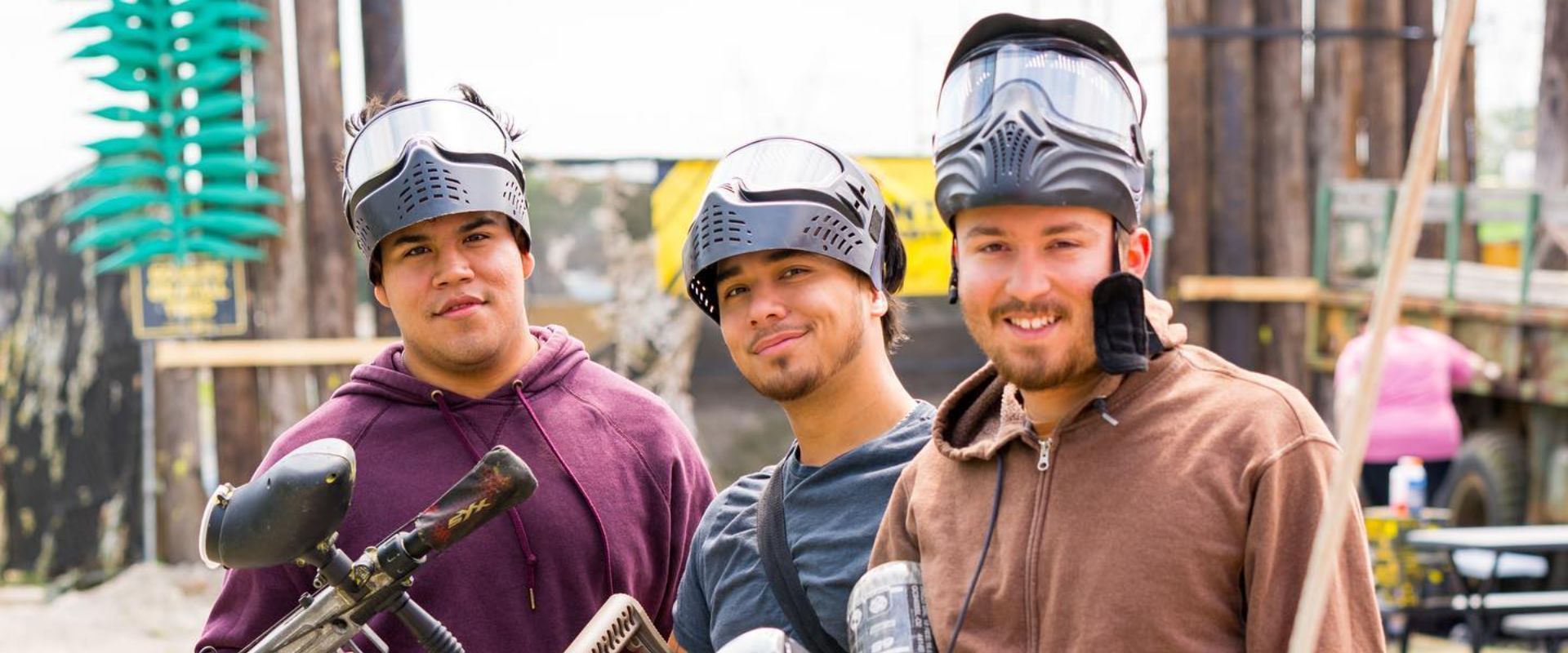 Three men wearing paintball helmets and goggles are standing next to each other.