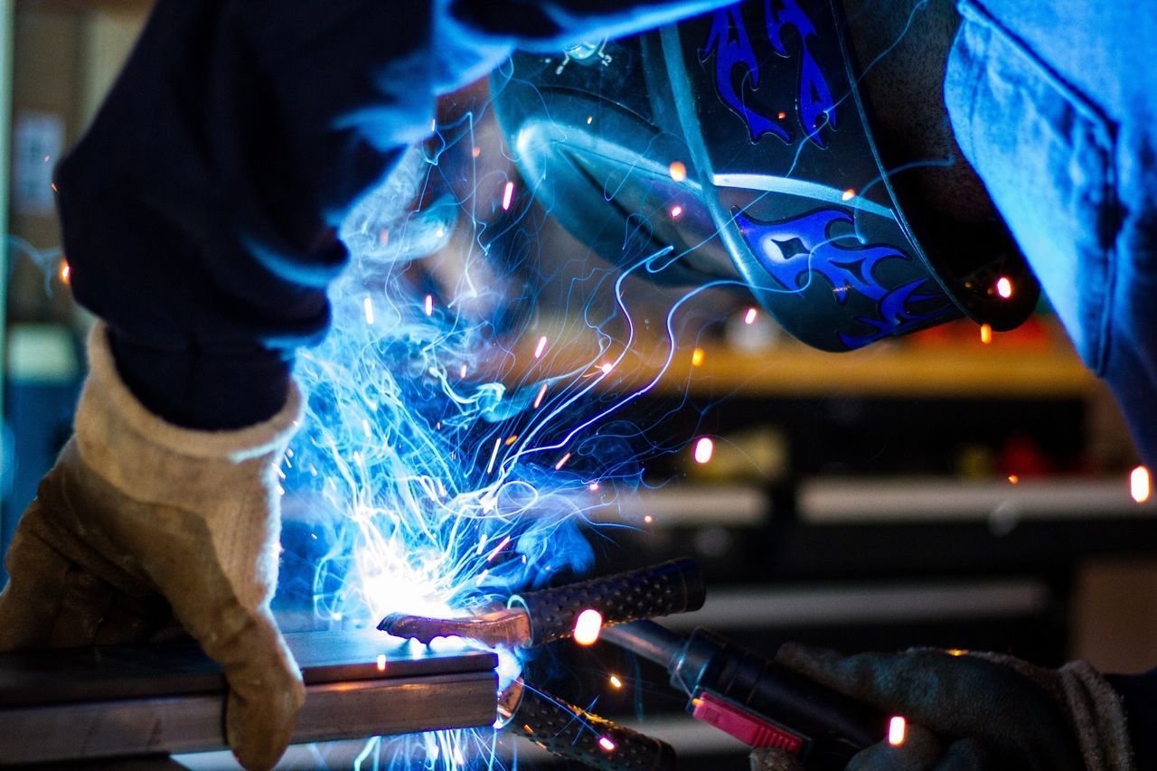 Un homme soude un morceau de métal dans une usine.