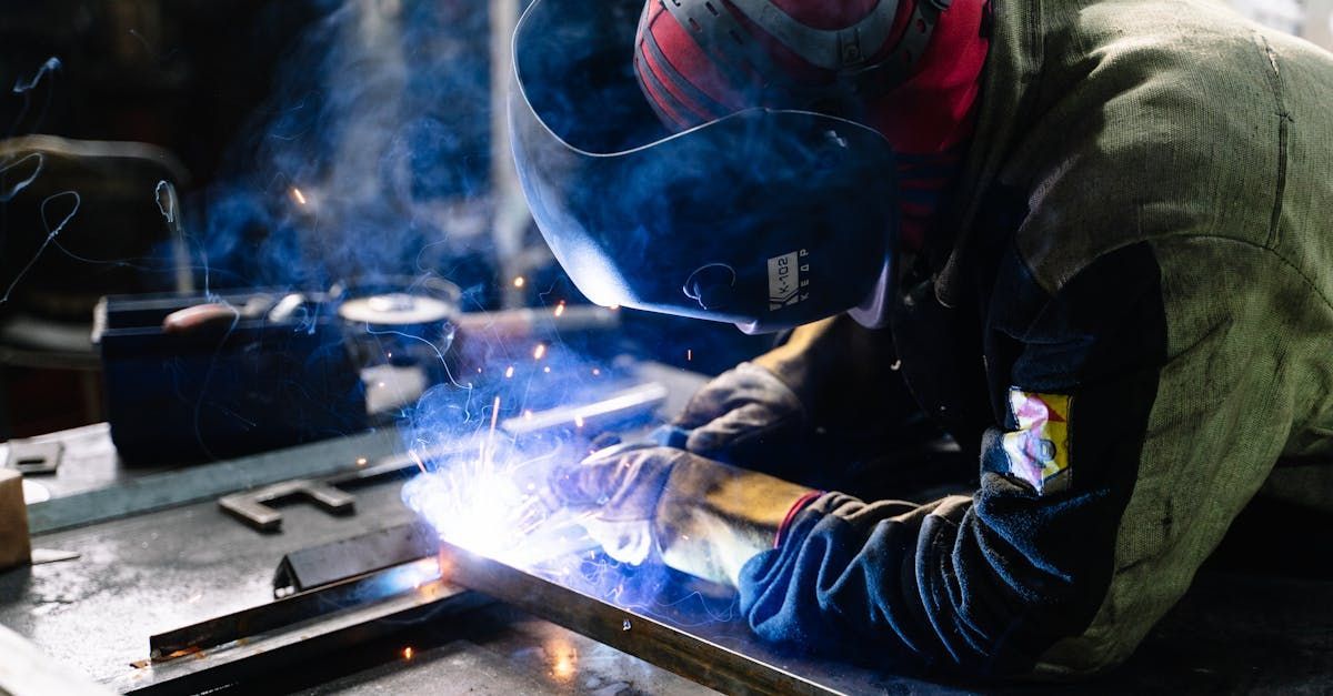 Un homme soude un morceau de métal dans une usine.