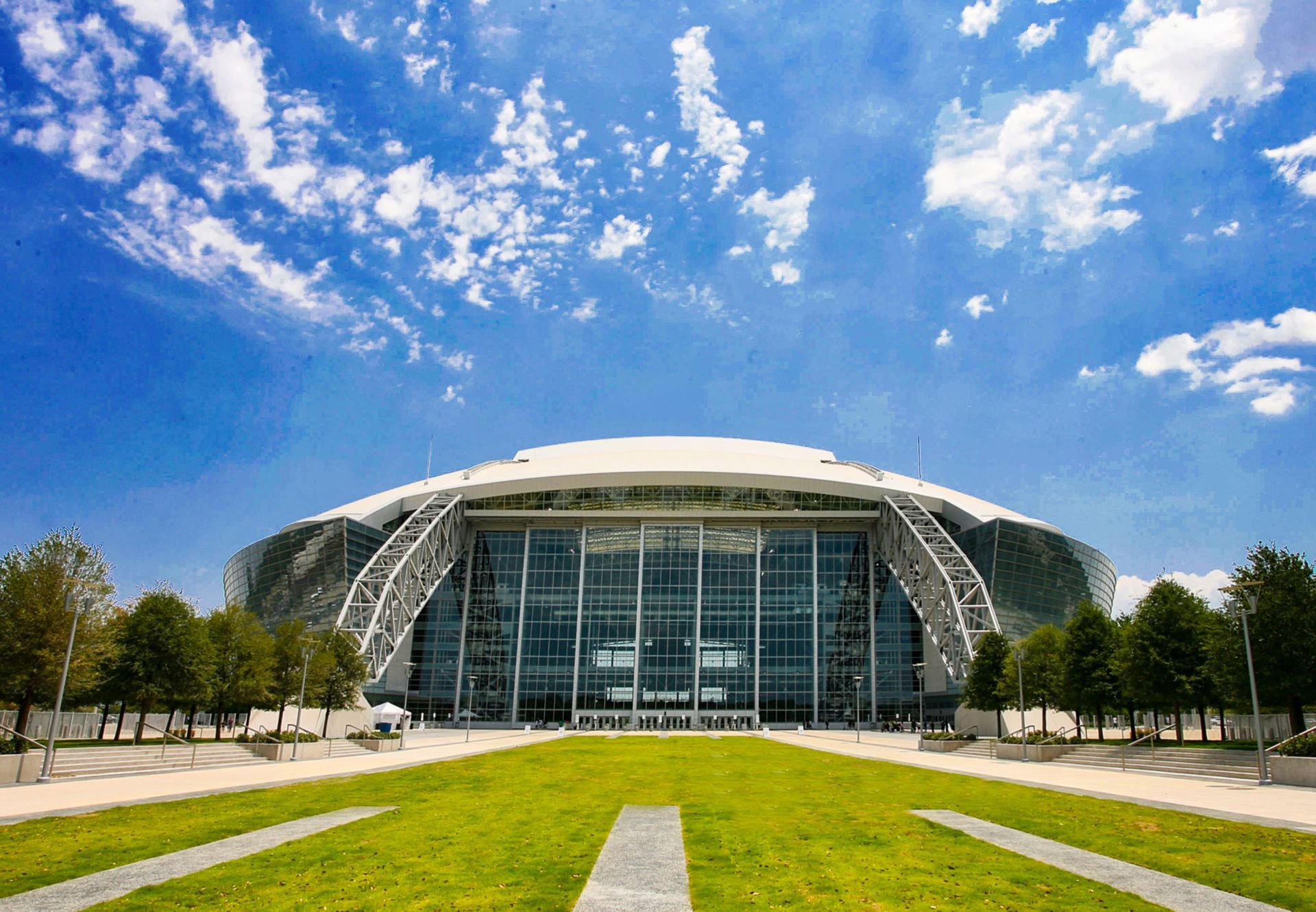 A large building with a dome on top of it is surrounded by grass and trees.