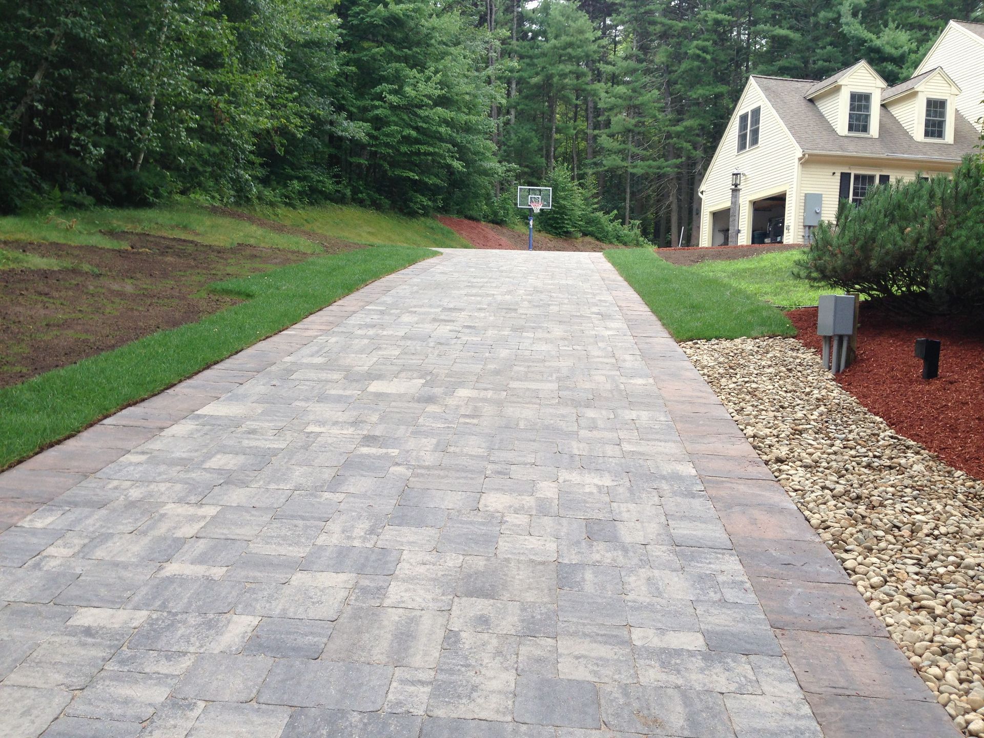 Workers applying blacktop sealer to an asphalt street using a spray, creating a protective coat to guard against weather elements.