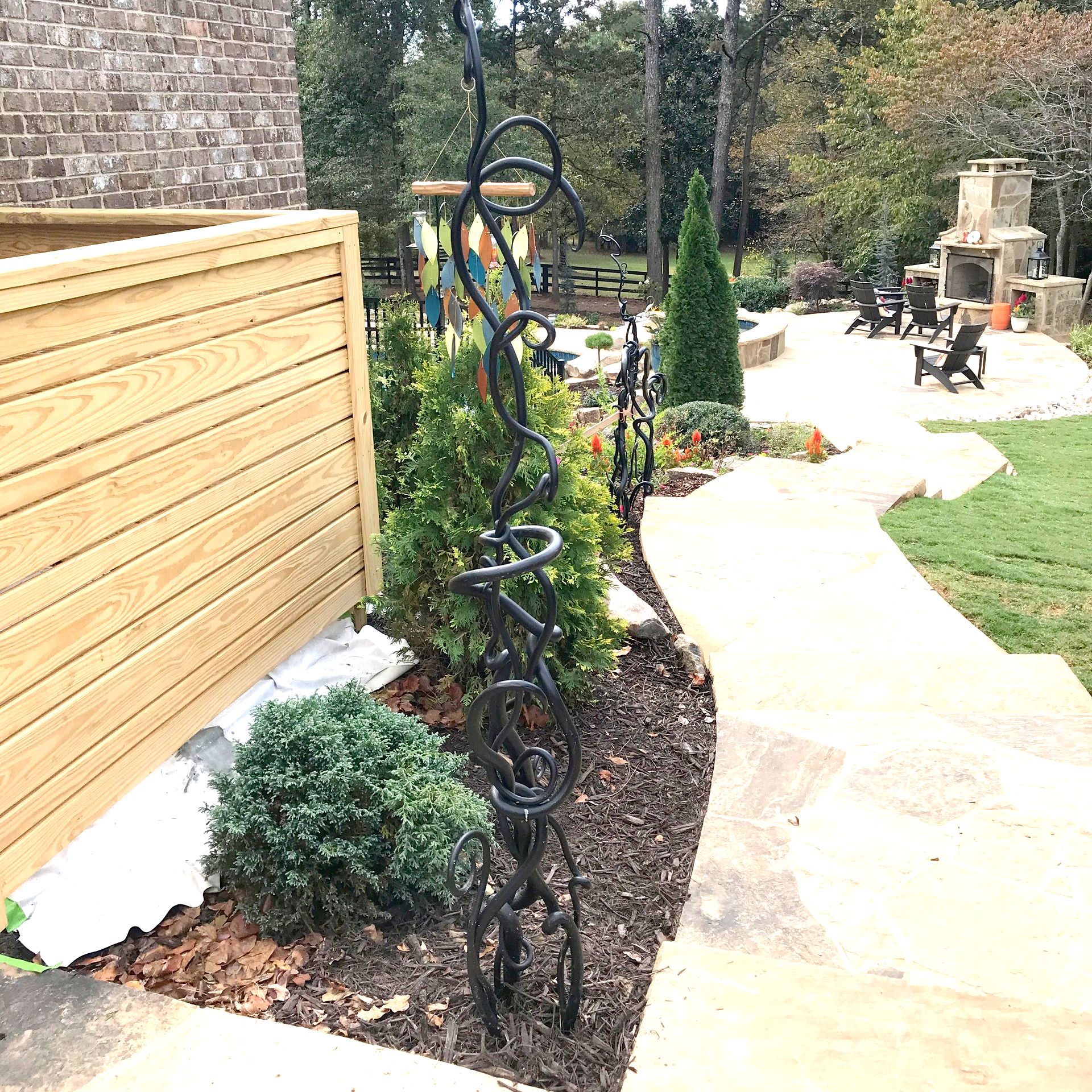 A walkway leading to a backyard with a fence and a fireplace.