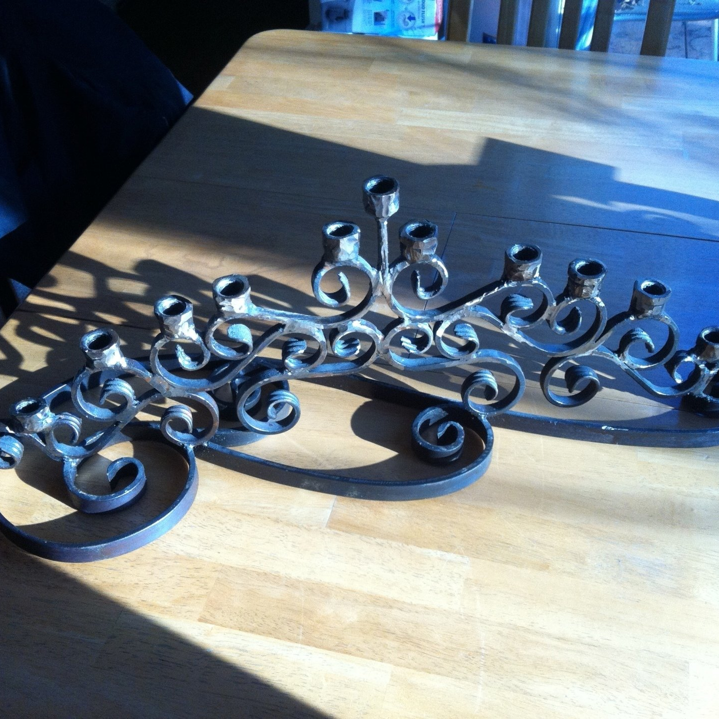 A wrought iron candle holder sits on a wooden table