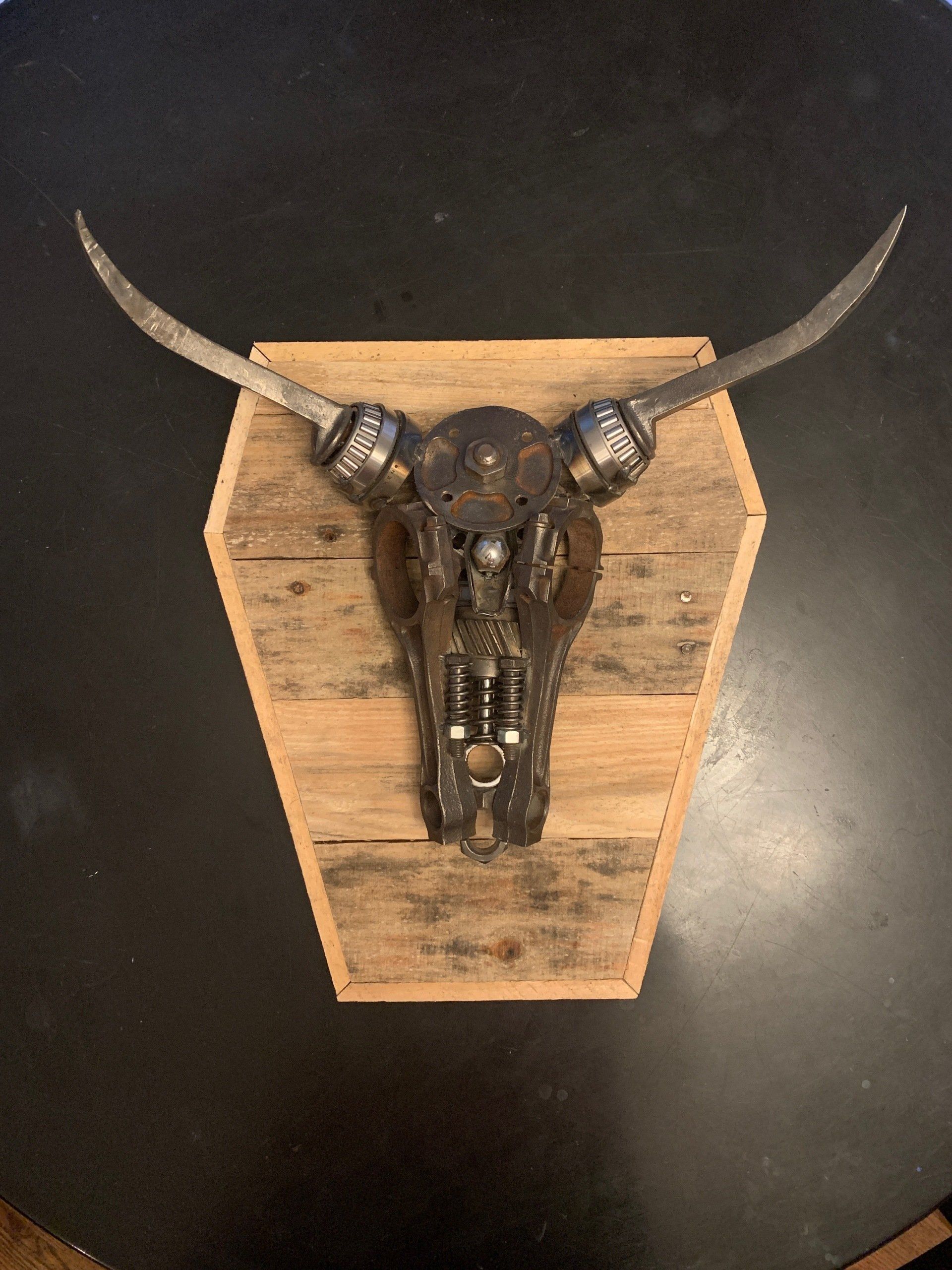 A bull skull is hanging on a wooden plaque on a table.
