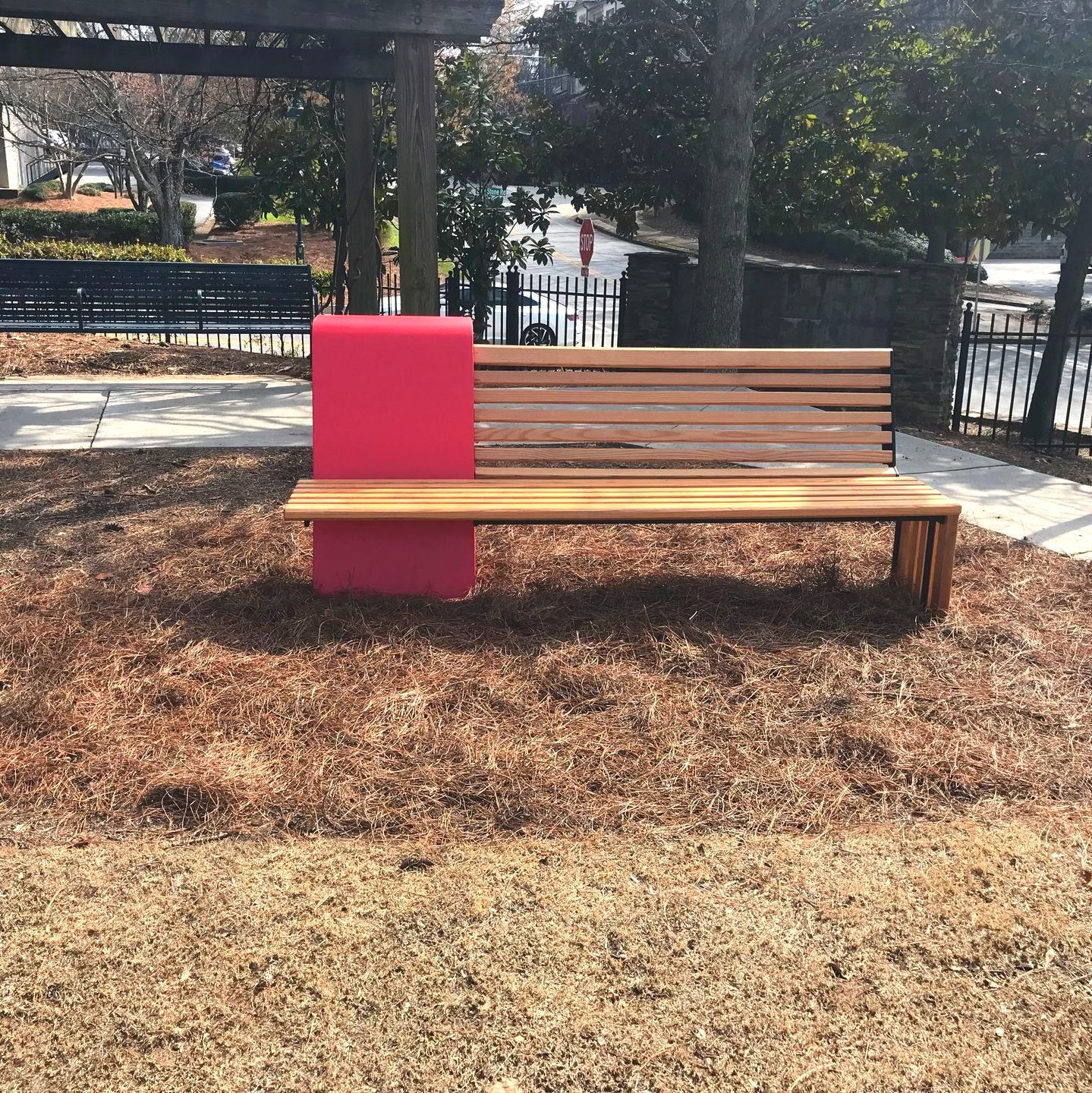 A wooden bench with a pink cushion on it