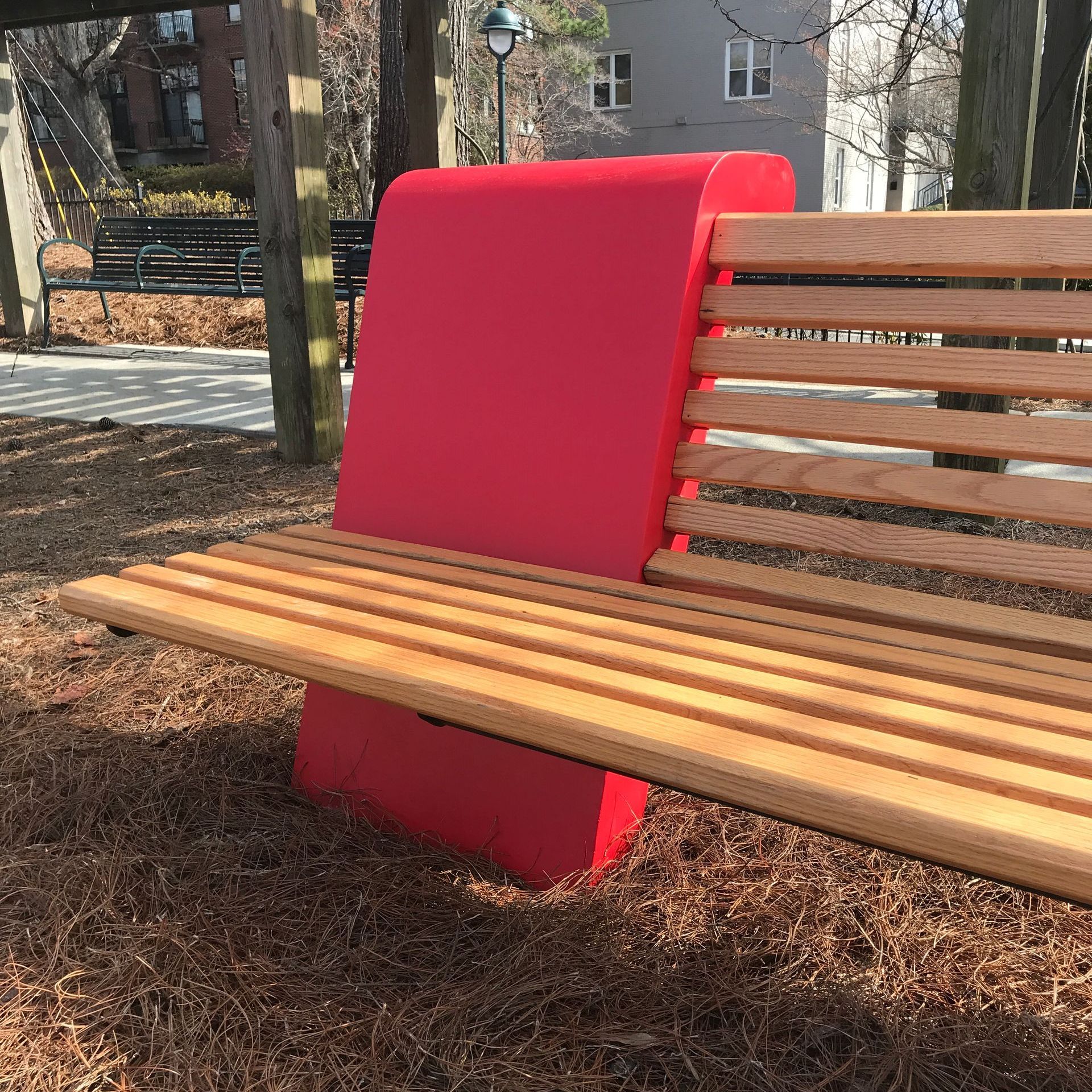 A wooden bench with a red backrest in a park