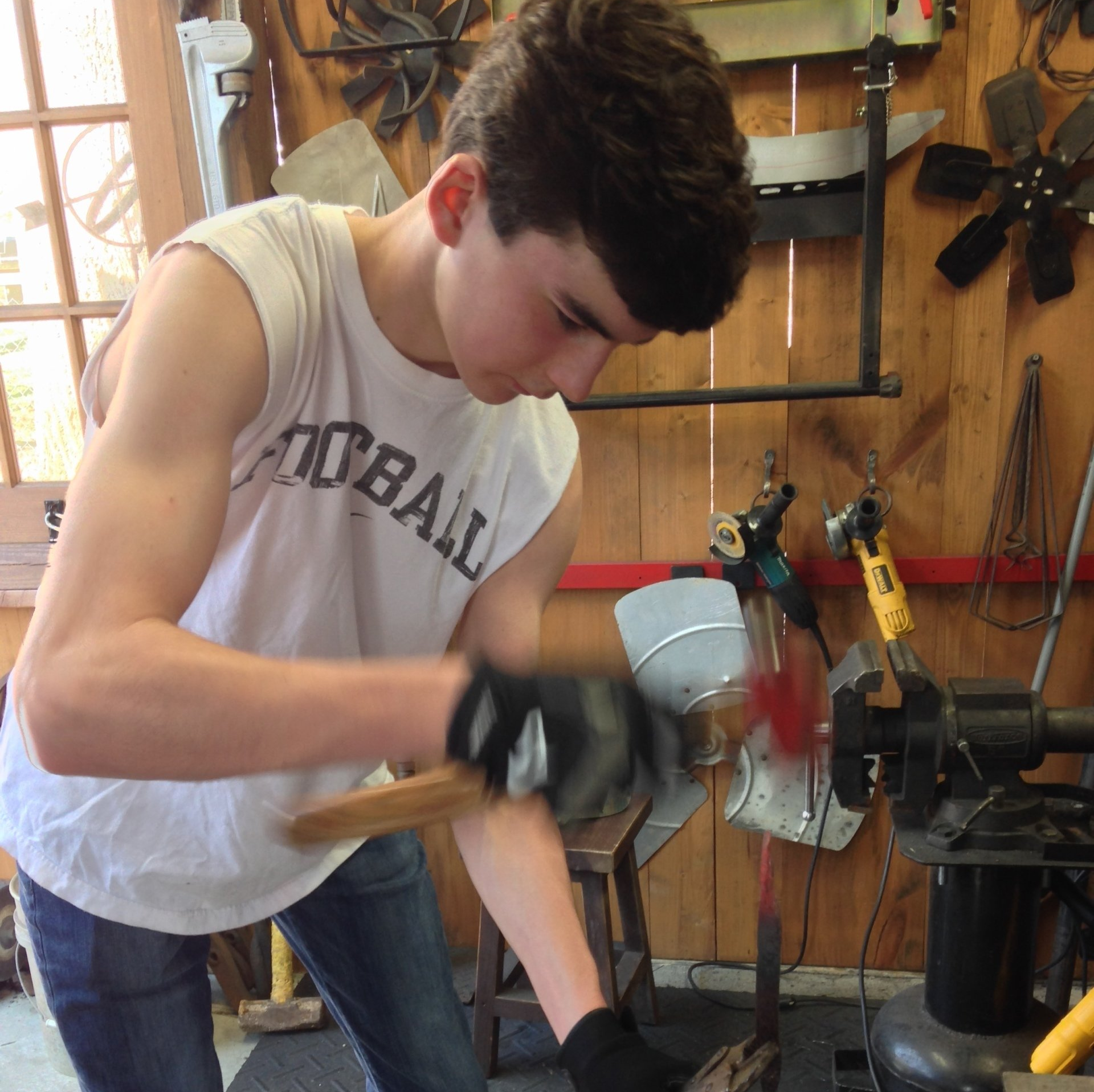 A young man wearing a shirt that says baseball is working with a hammer