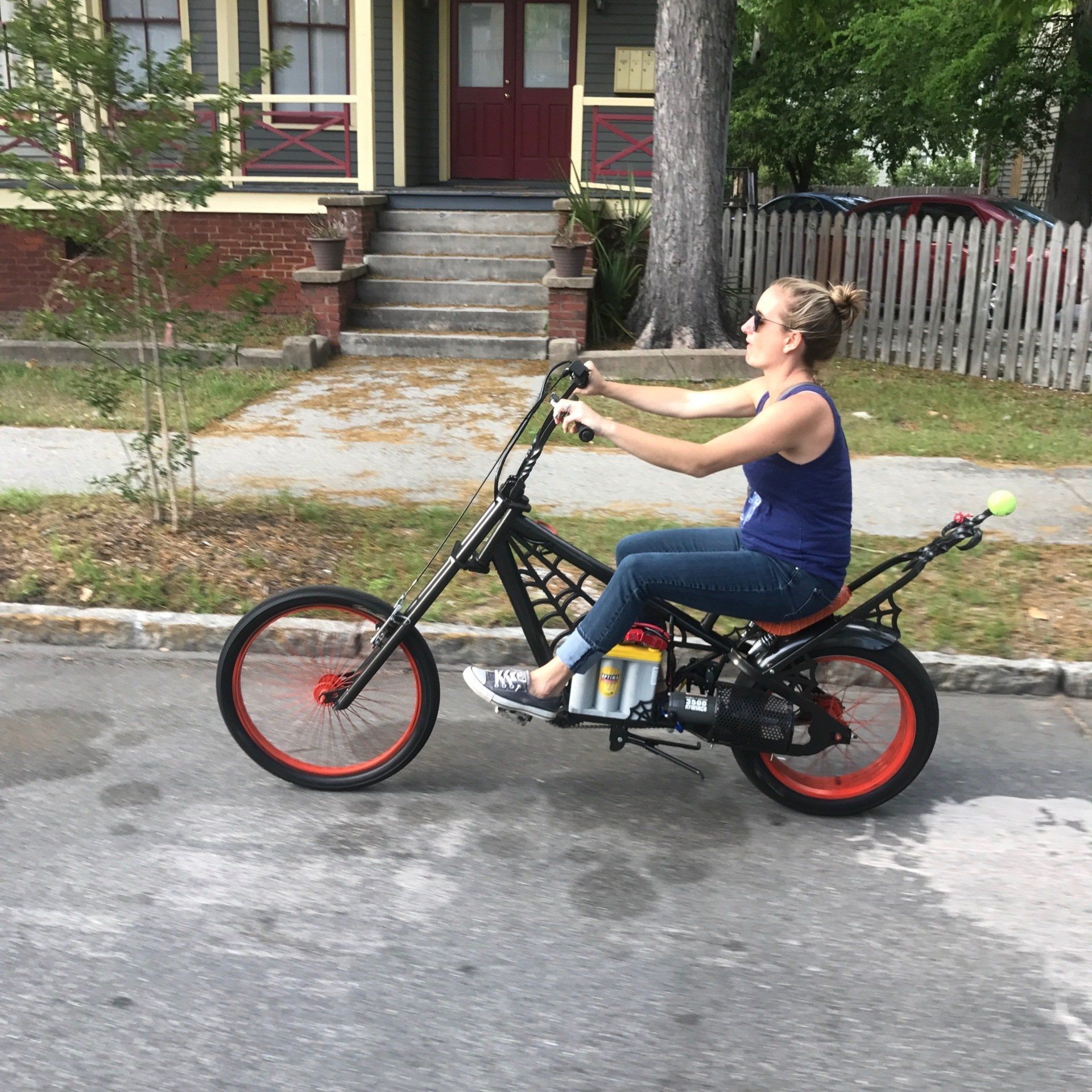 A woman is riding an electric chopper bike down a street