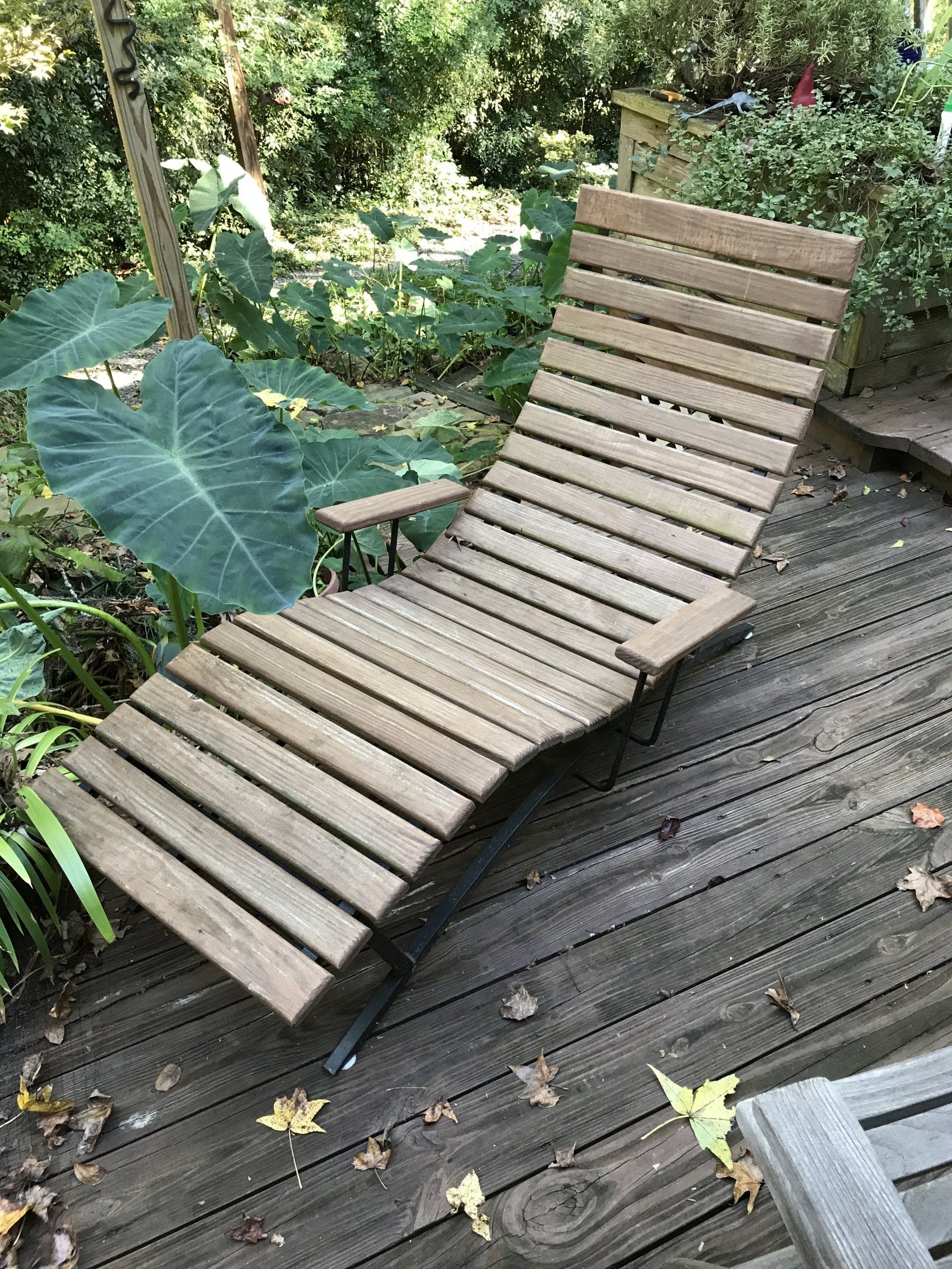 A wooden lounge chair is sitting on a wooden deck.