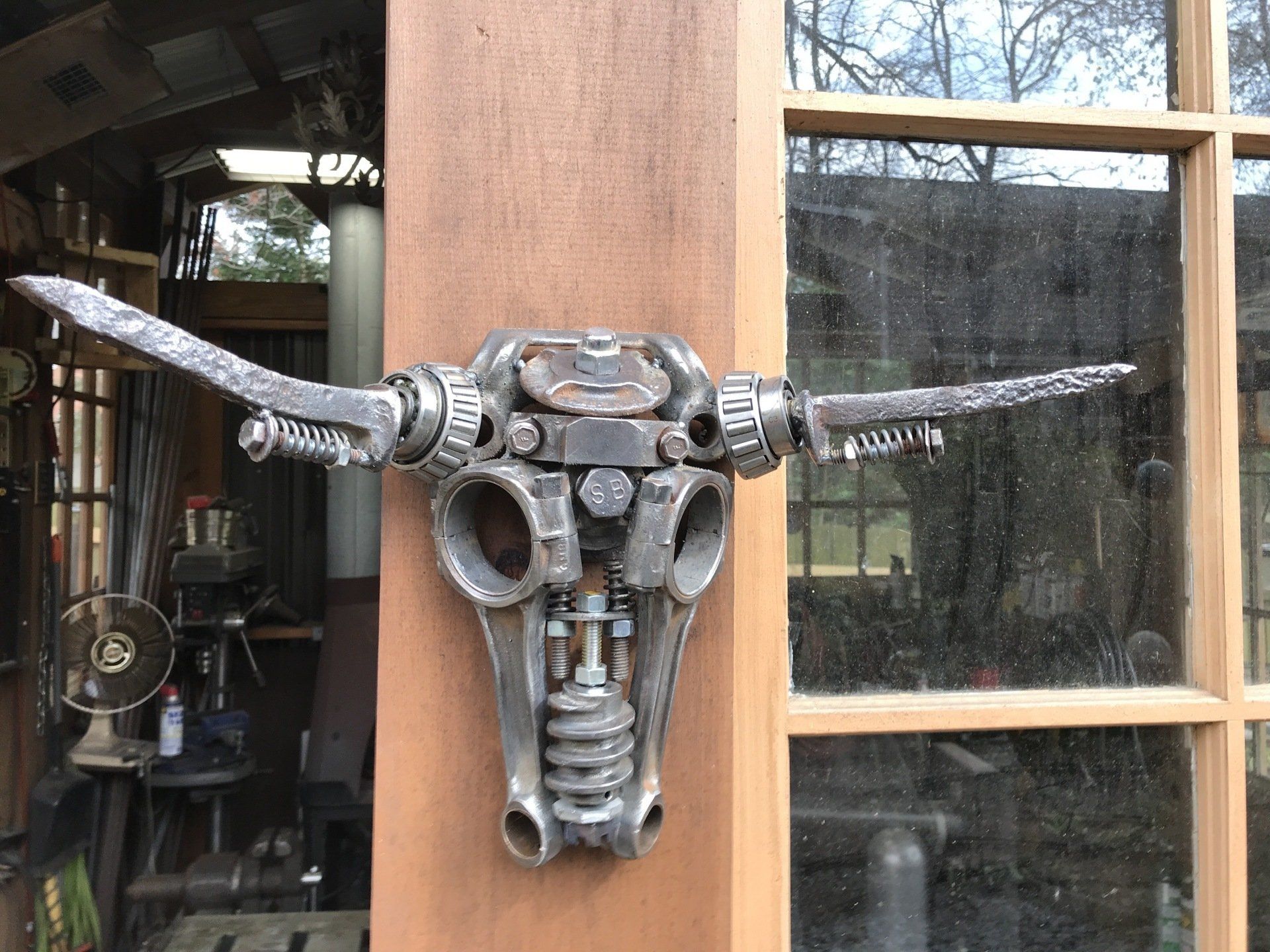 A metal bull skull is hanging on a wooden wall.