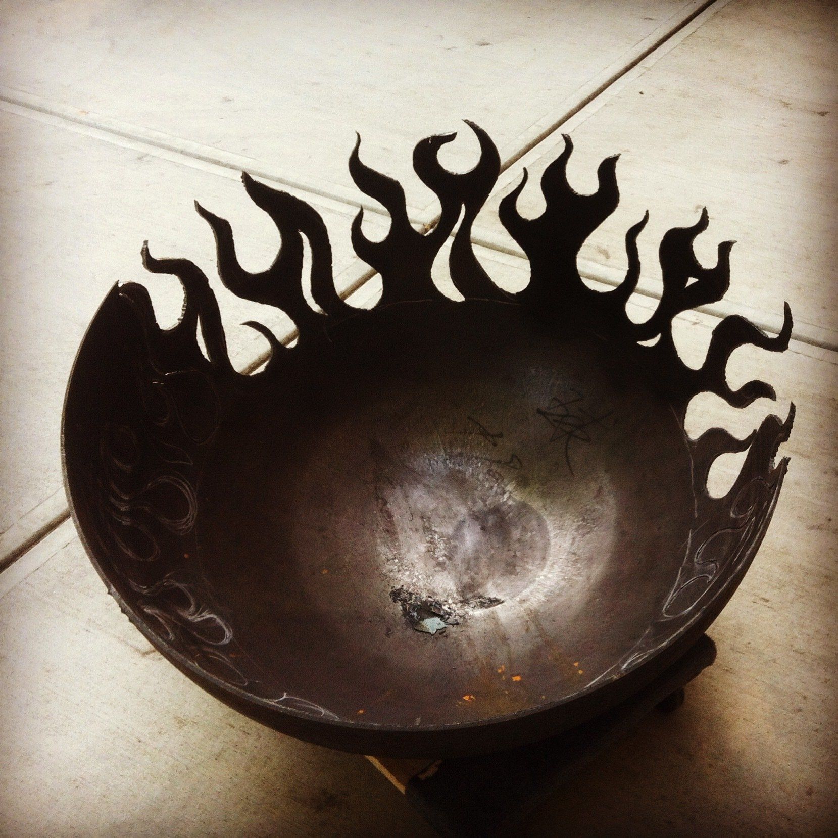 A metal bowl with a design of flames on it