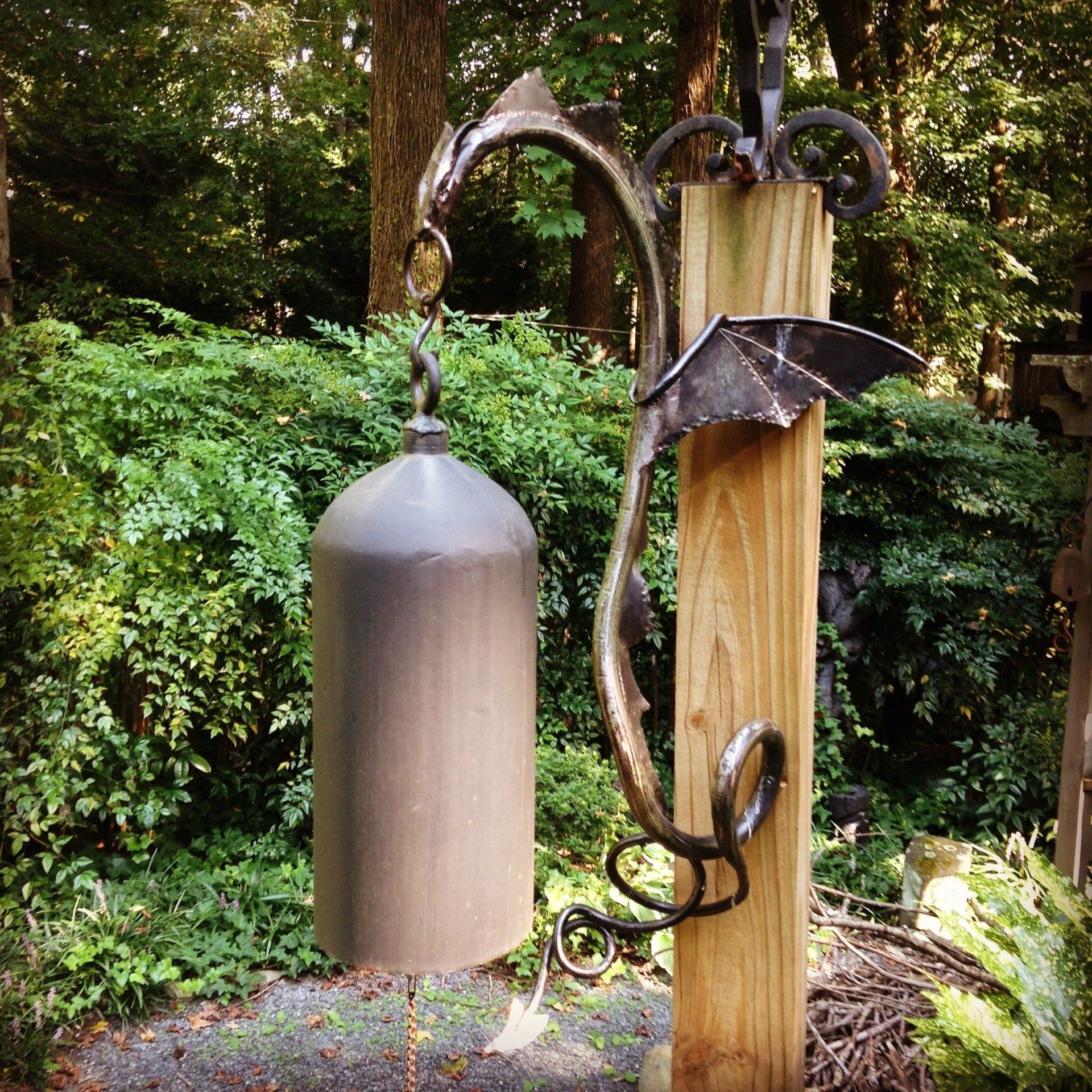 A bell with a dragon on it is hanging from a wooden post