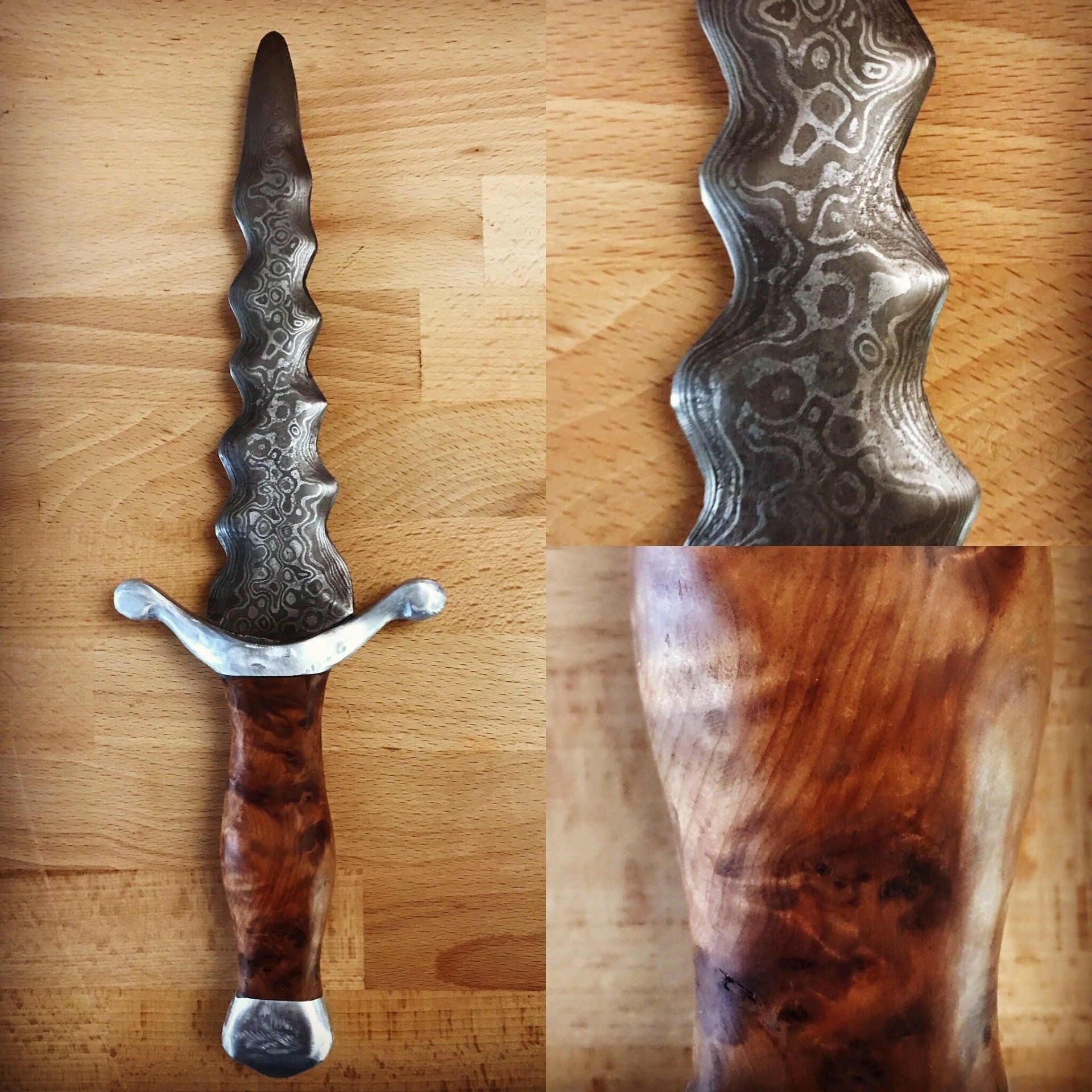 A dagger with a wooden handle, a Damascus steel knife, sits on a wooden table