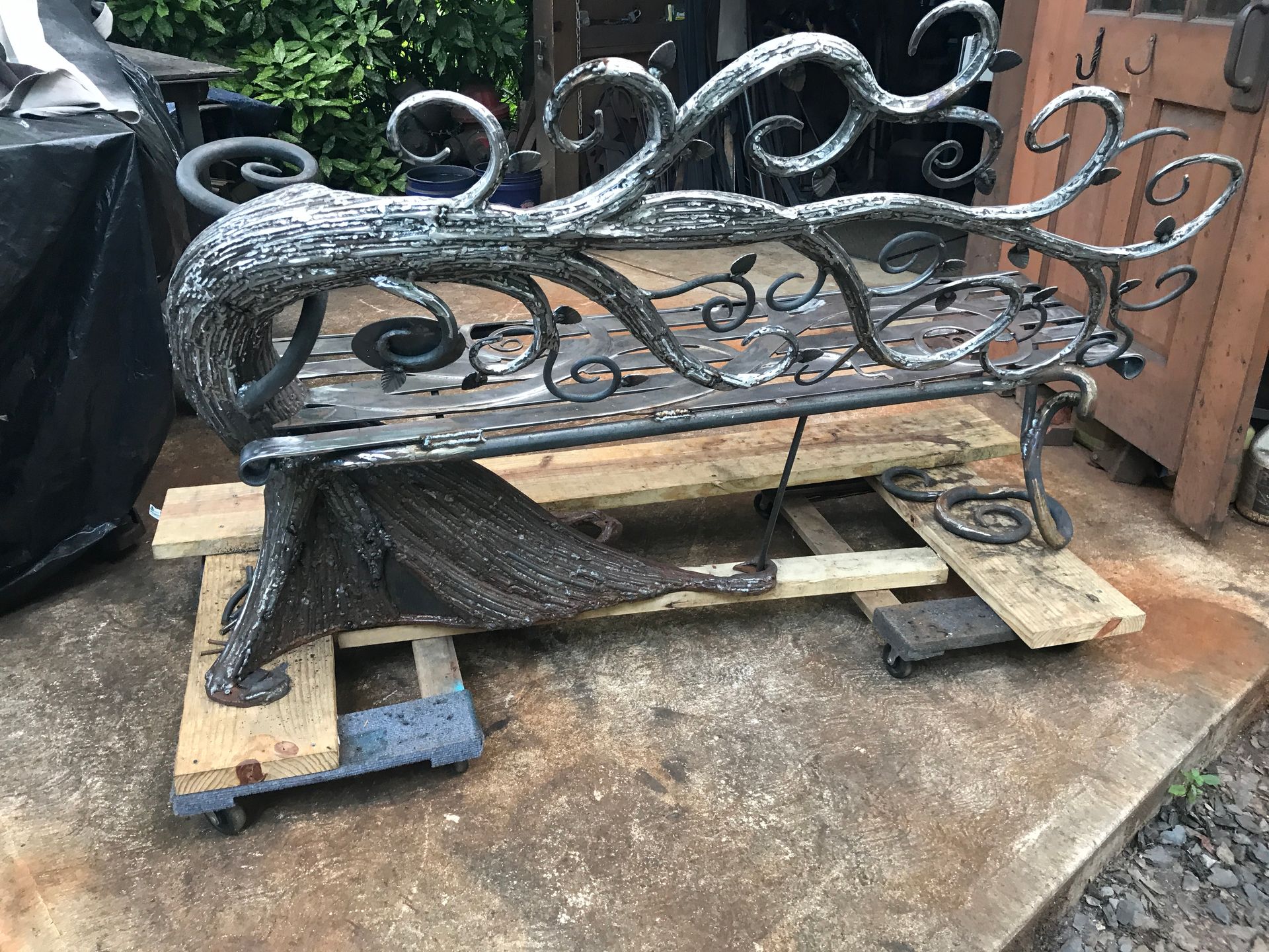 A wrought iron bench is sitting on top of a wooden pallet.