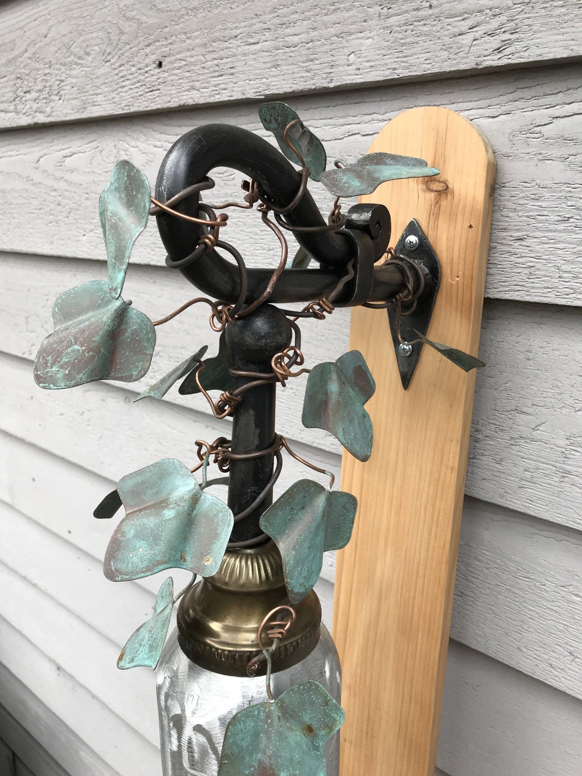 A lamp is hanging on a wooden wall next to a house.