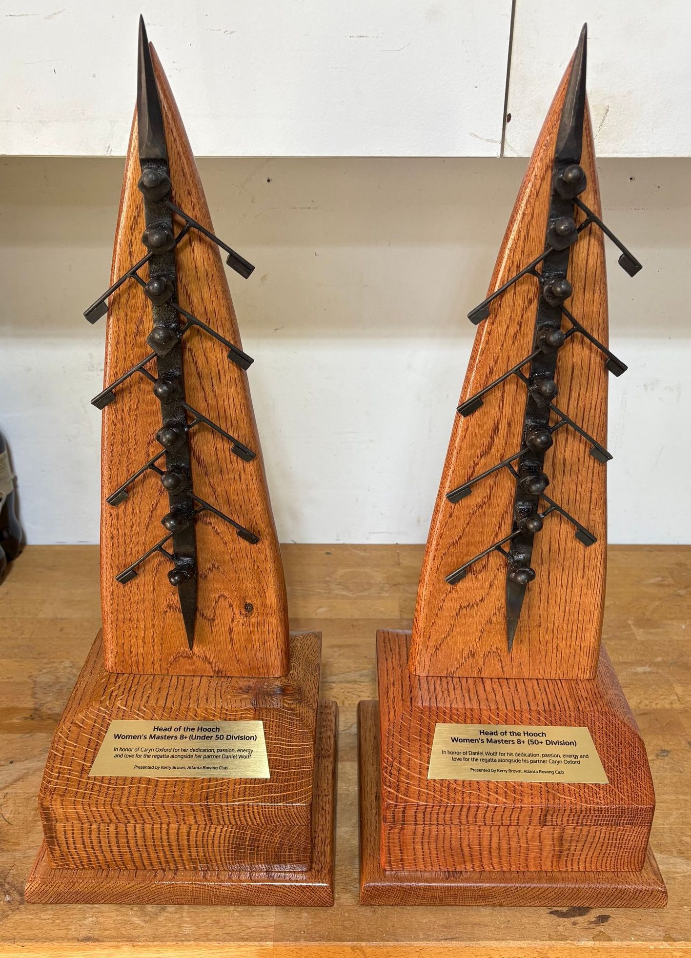 Two wooden trophies are sitting on a wooden table.