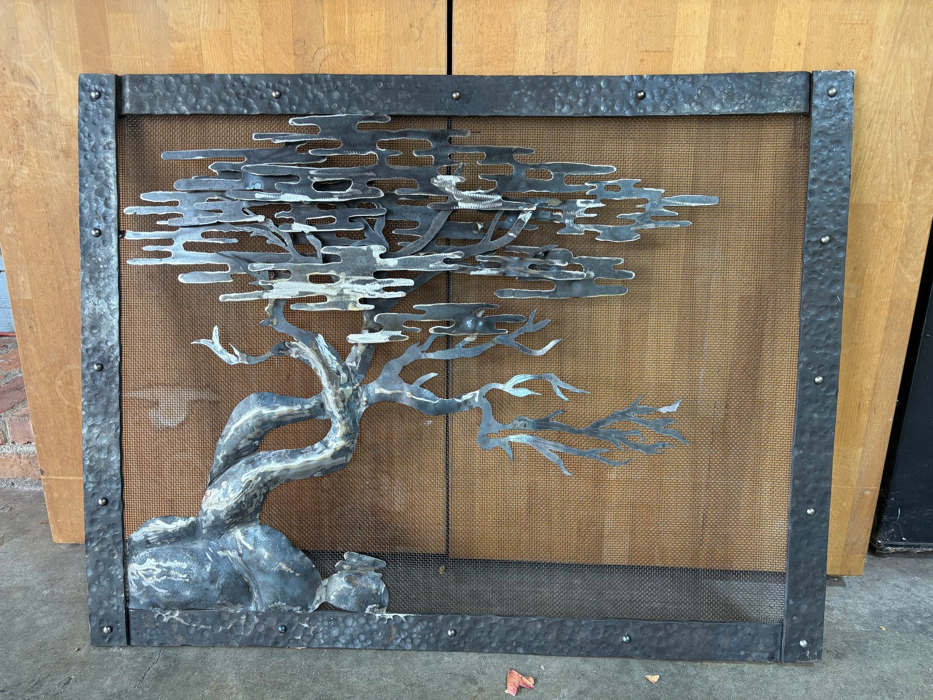 A metal fireplace screen with a tree on it