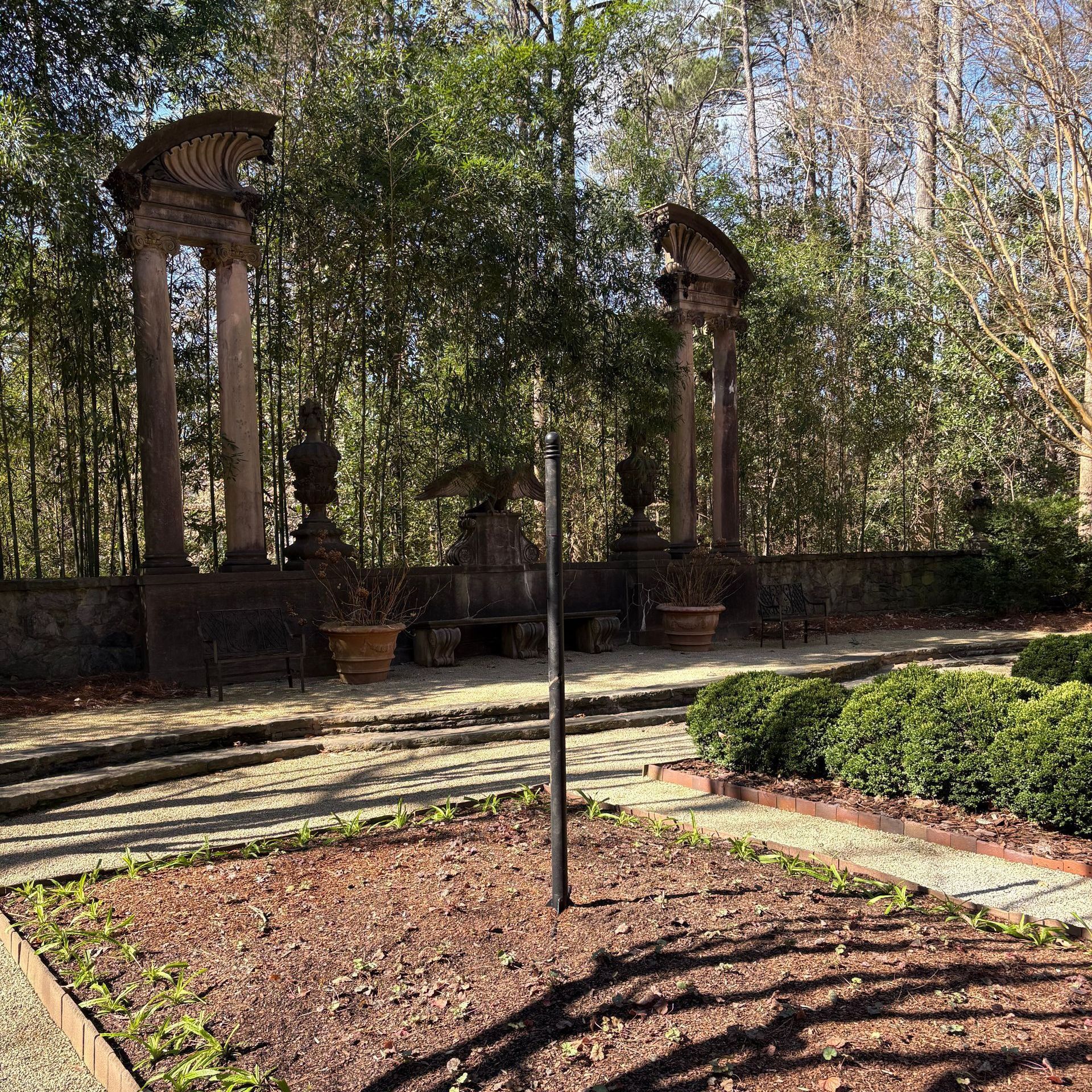 A garden with a labyrinth in the middle of it and trees in the background.