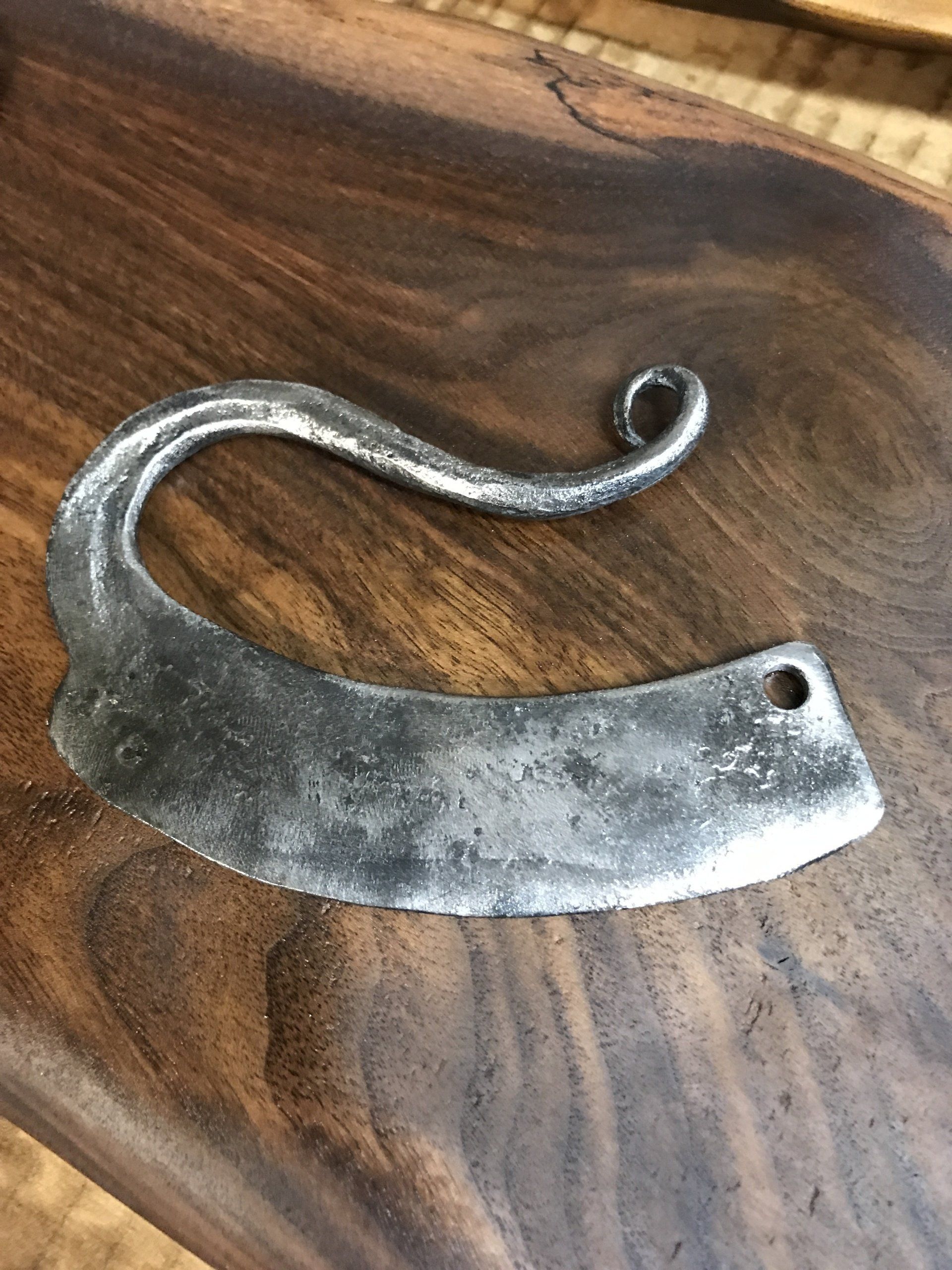 A metal object is sitting on top of a wooden table—cheese cutter.