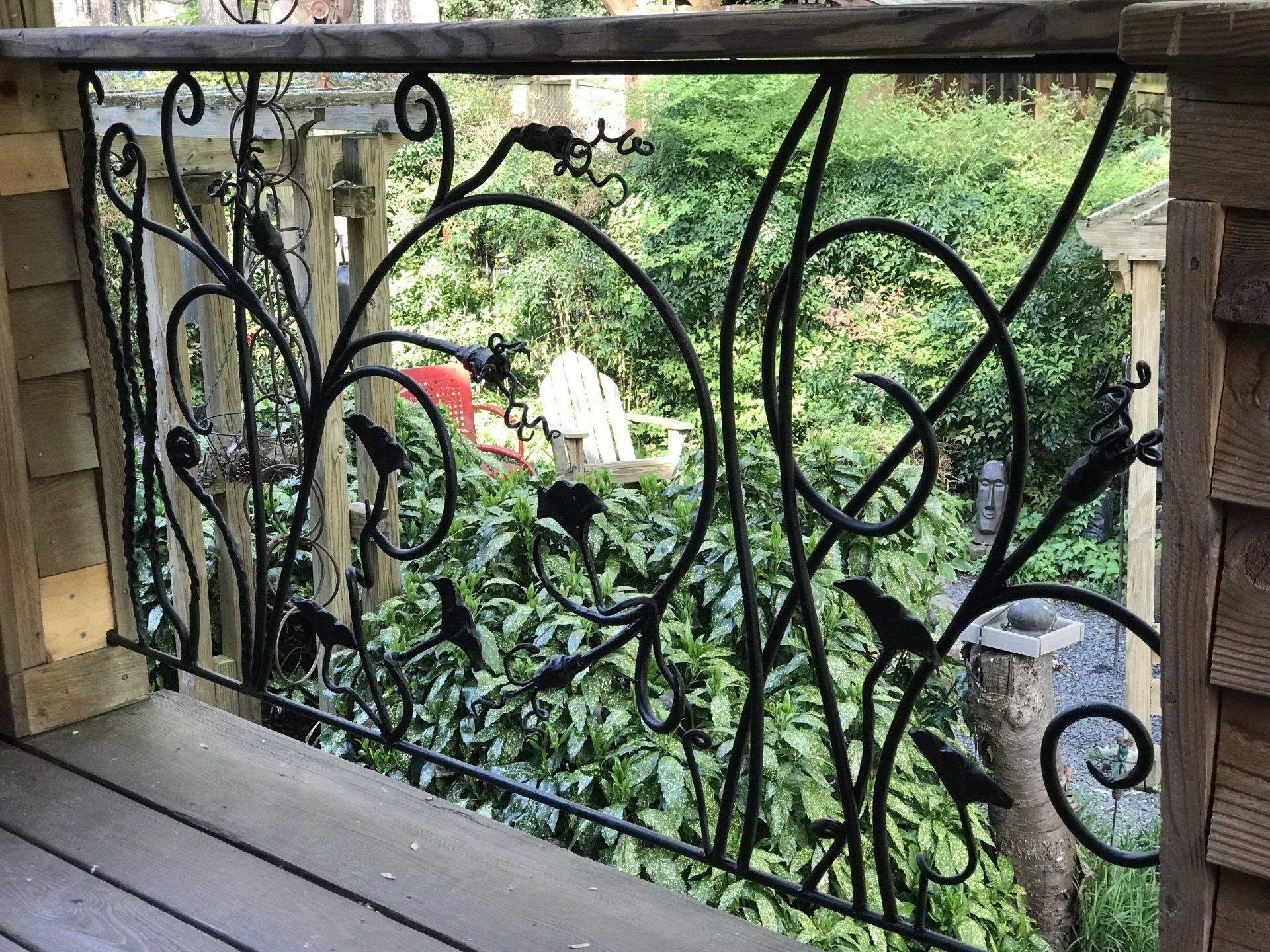 A wrought iron railing with birds on it is on a deck.