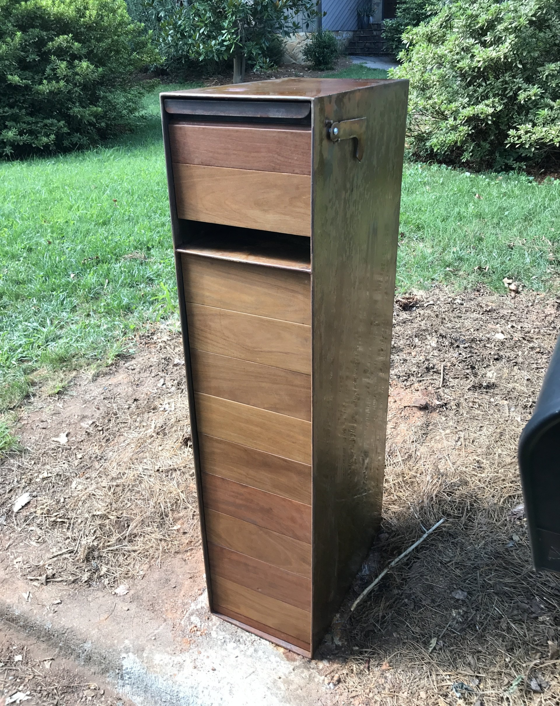 A wooden mailbox is sitting in the middle of a grassy field.