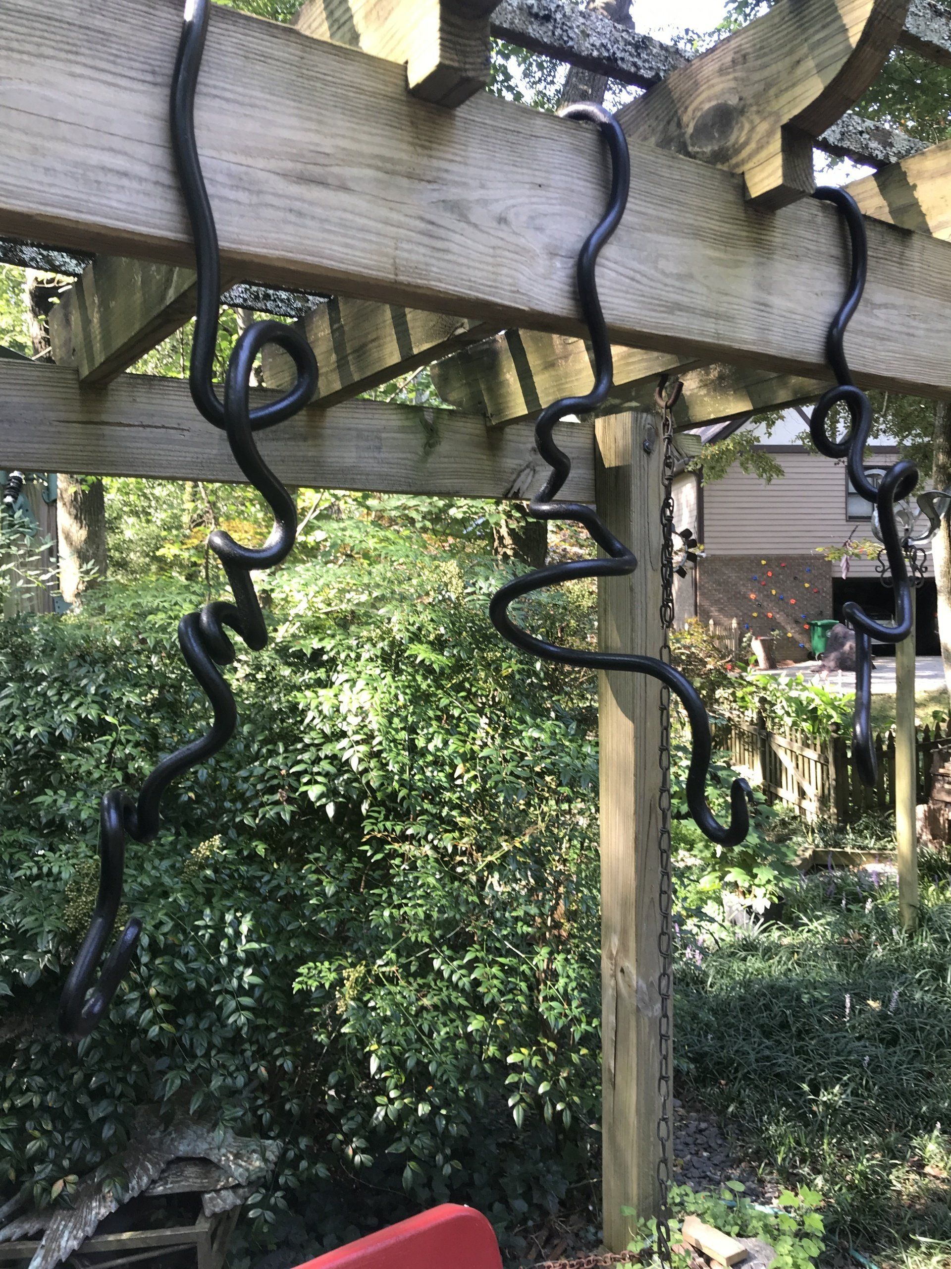 A wooden pergola with a snake hanging from it