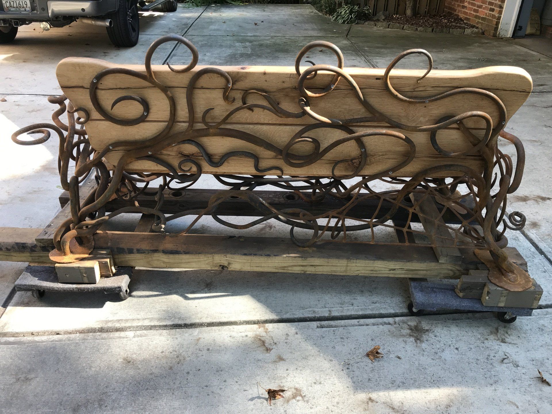 A wooden bench with a wrought iron frame is sitting on a concrete surface.