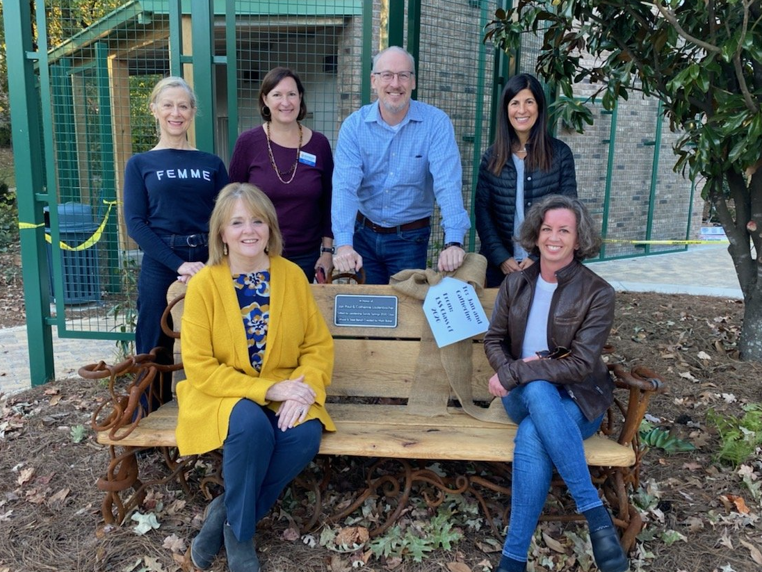 A group of people are sitting on a wooden bench.