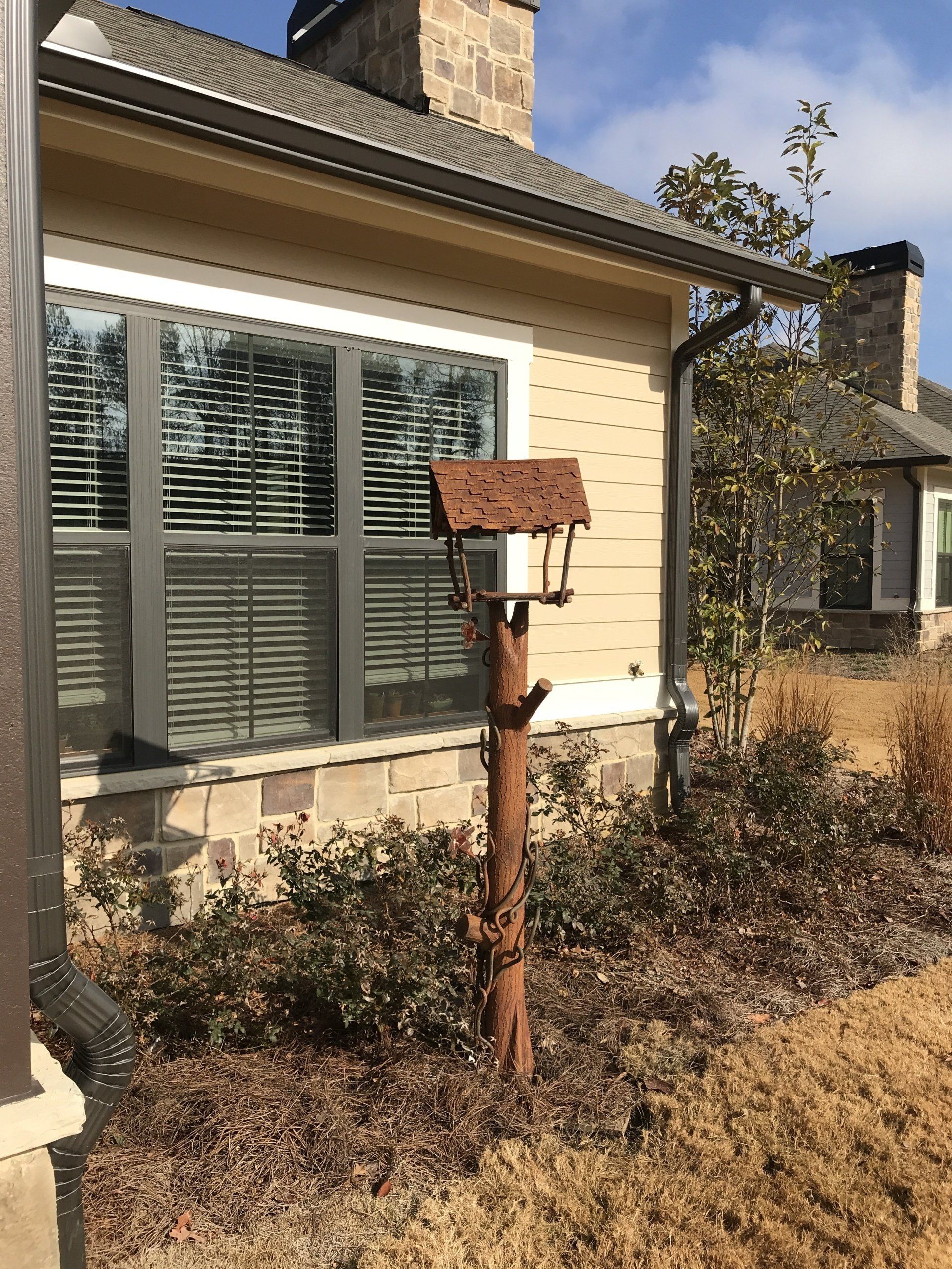 A bird feeder is sitting in front of a house.