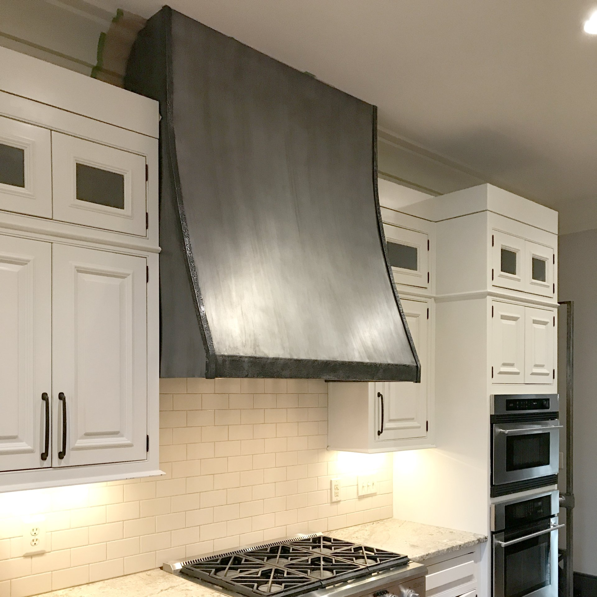 A kitchen with white cabinets and a stove top oven