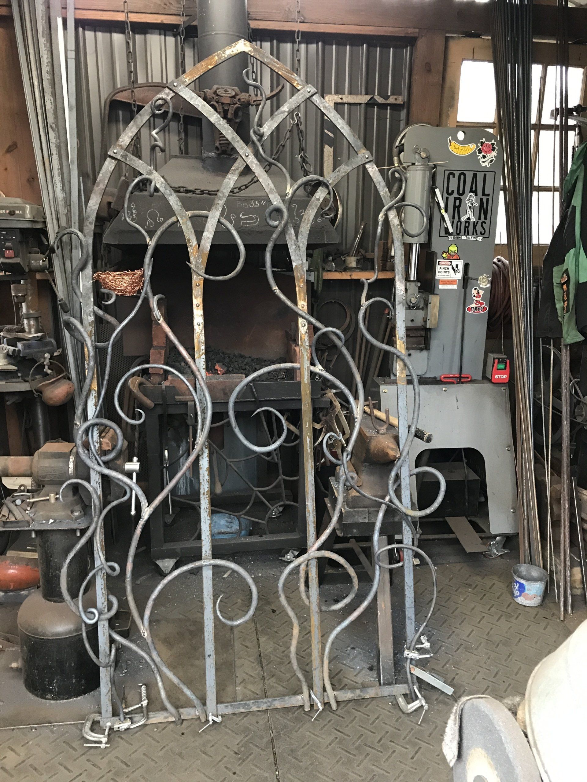 A wrought iron gate is sitting in front of a fireplace in a workshop.
