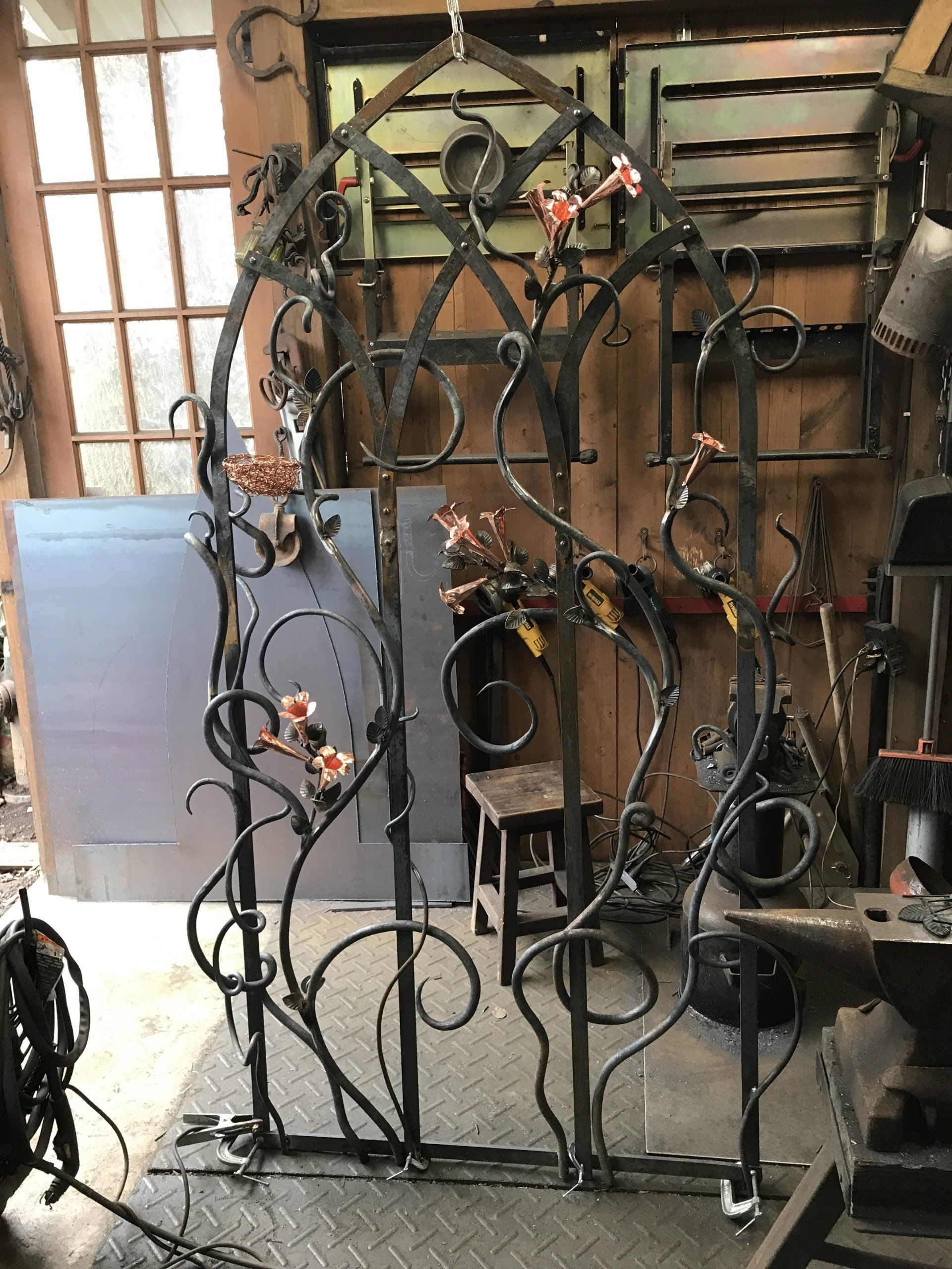 A wrought iron gate with flowers on it is in a workshop.