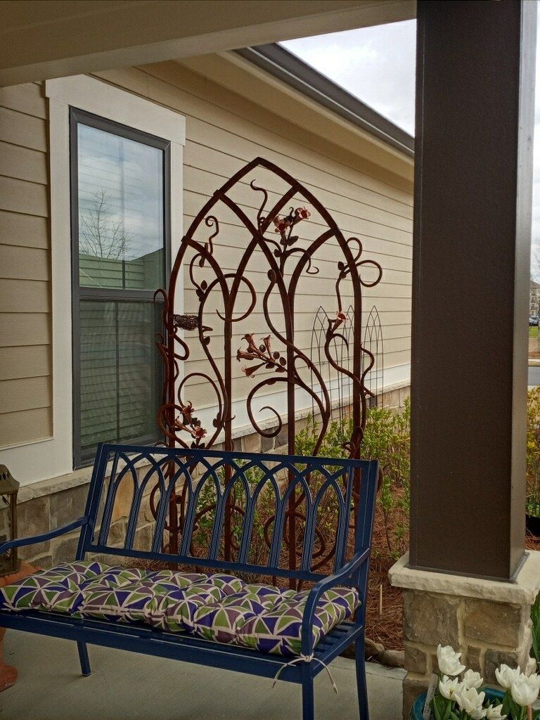 A blue bench is sitting on a porch in front of a house.